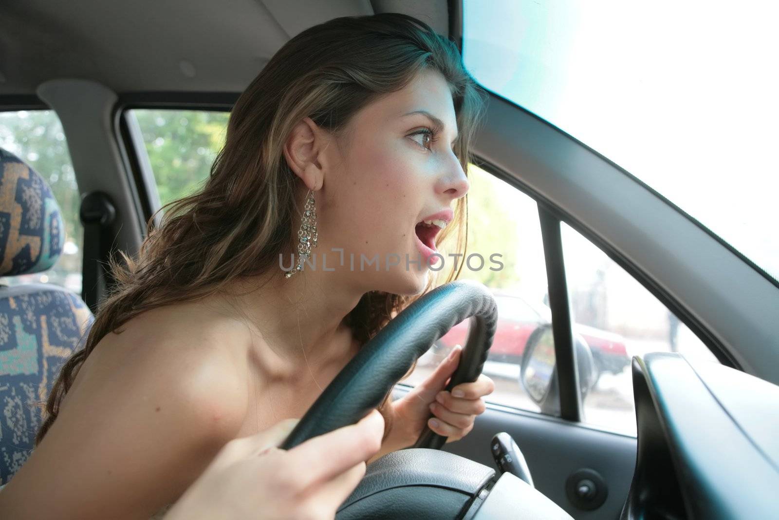 emotional brunette driver keeps steering wheel a hand and looks at road