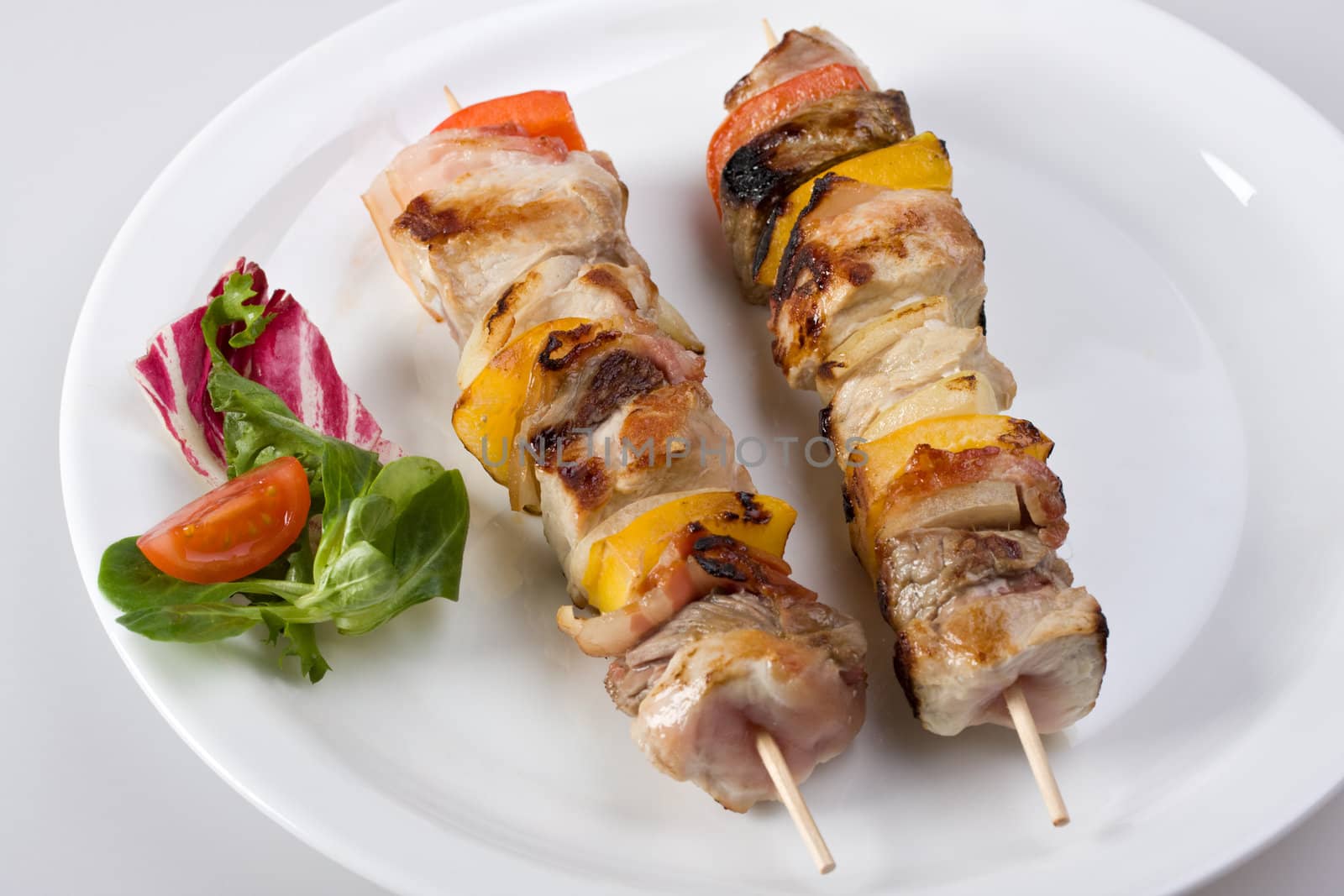 shashlik on a plate with a tomato and salad leaf