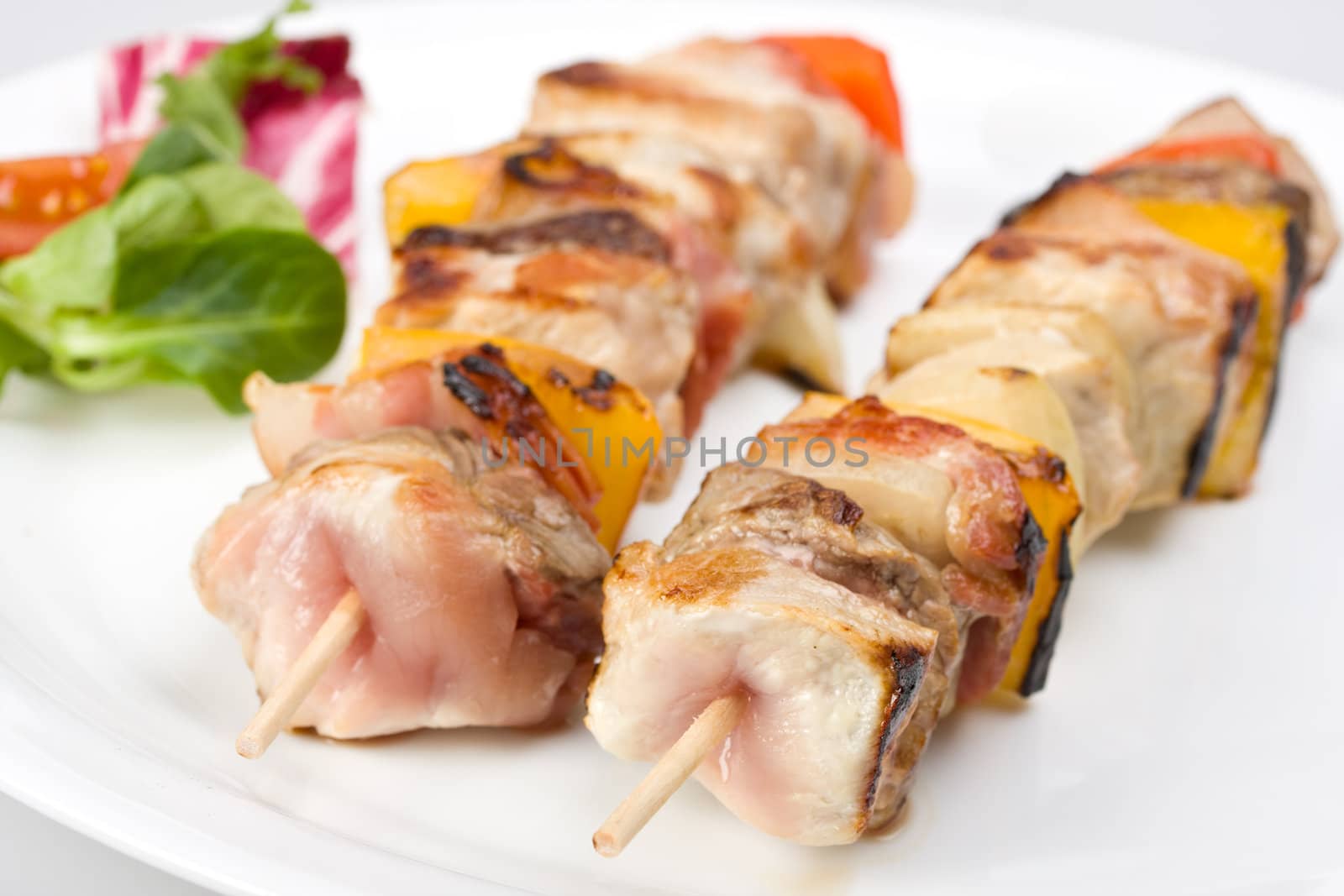 shashlik on a plate with a tomato and salad leaf