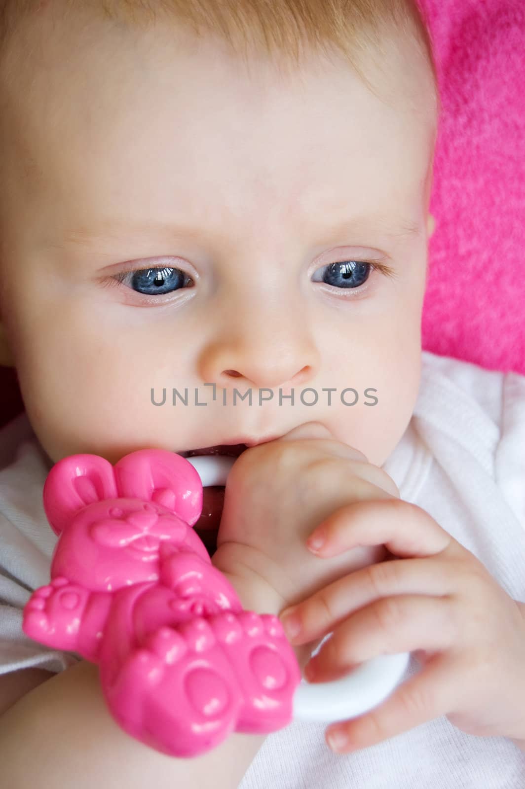 Blue eyed baby girl playing with toy