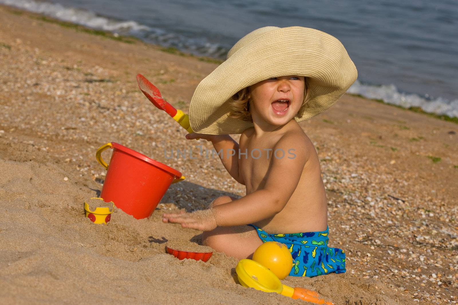 little girl in the bonnet plaing with sand
