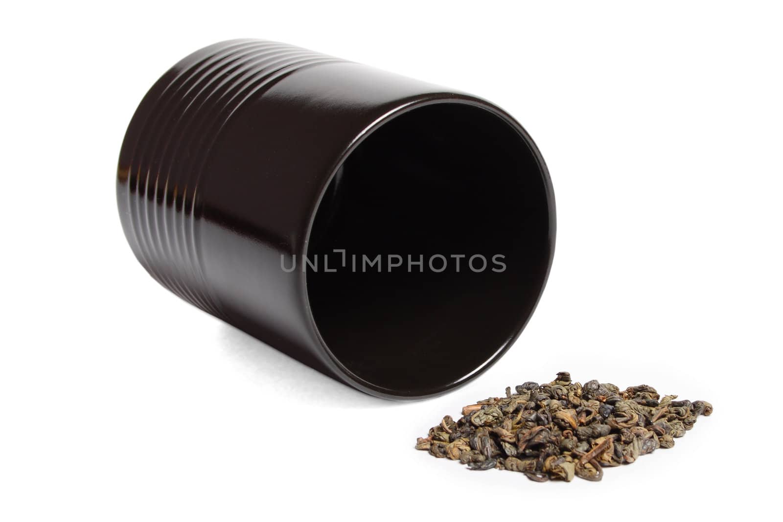 black cup heap of green tea leaves isolated over white