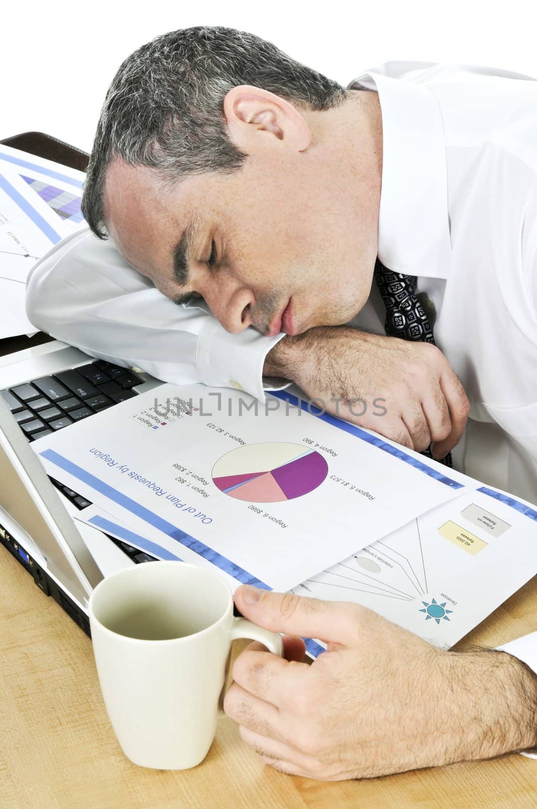 Tired businessman asleep at his desk isolated on white background