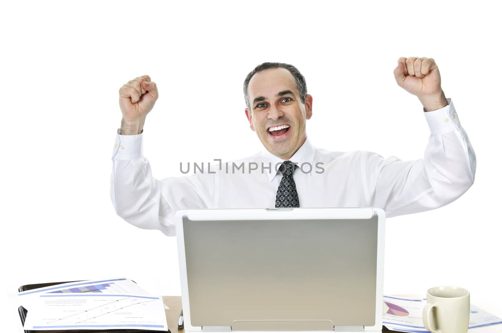 Happy businessman raising his arms sitting at his desk isolated on white background