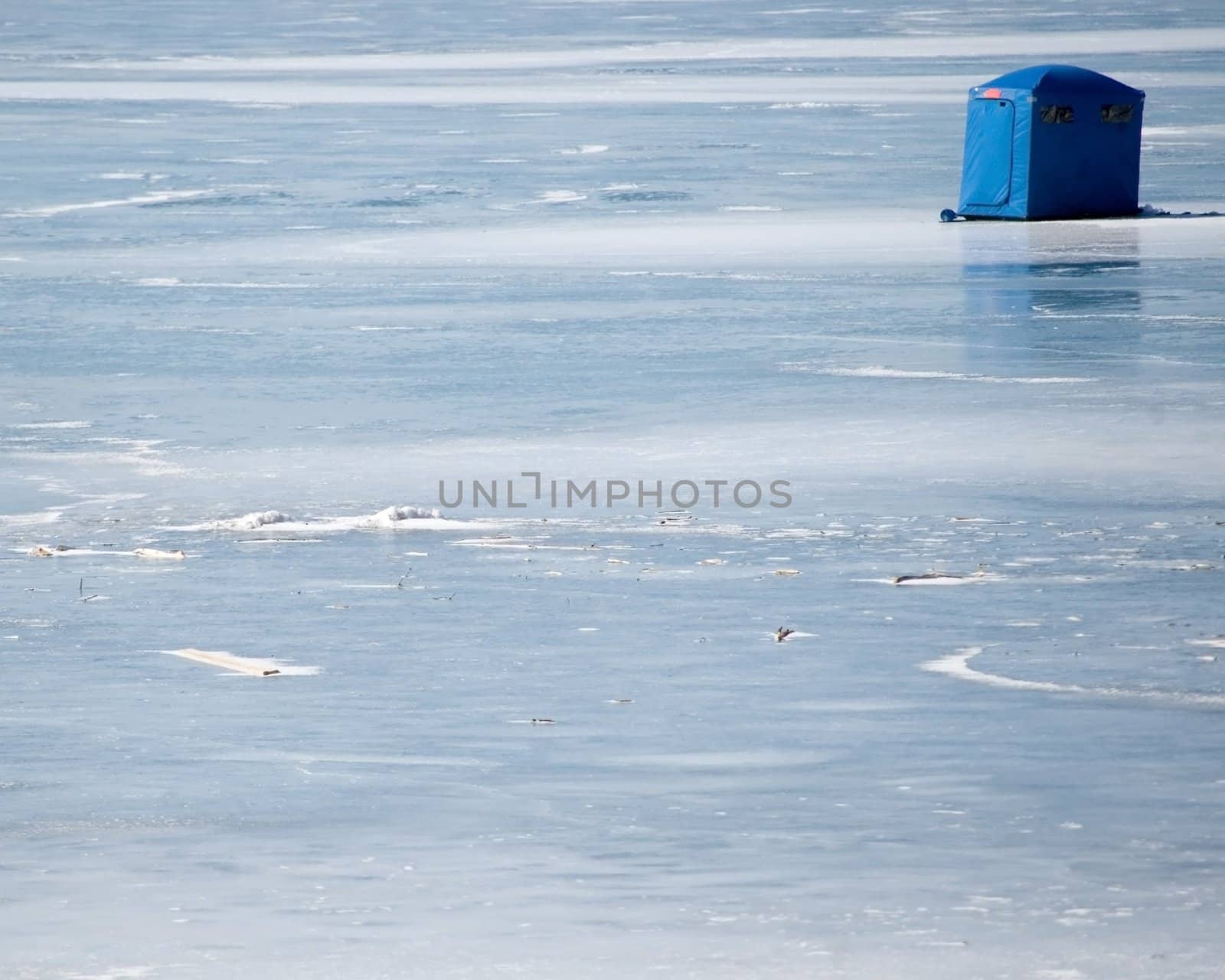 A ice fishing tent set up on a lake in the winter season.