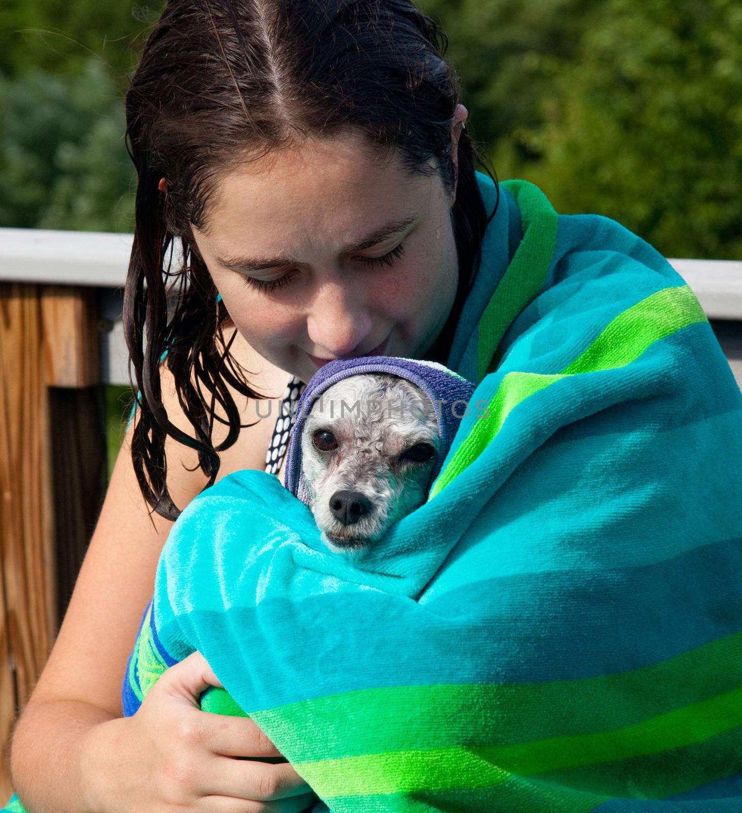 Girl cuddling a wet dog in a towel after a swim