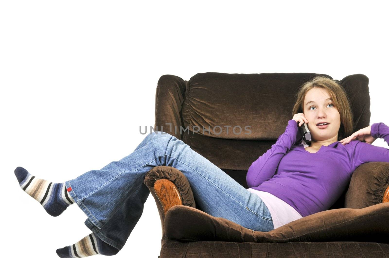 Teenage girl talking on a phone sitting in an armchair