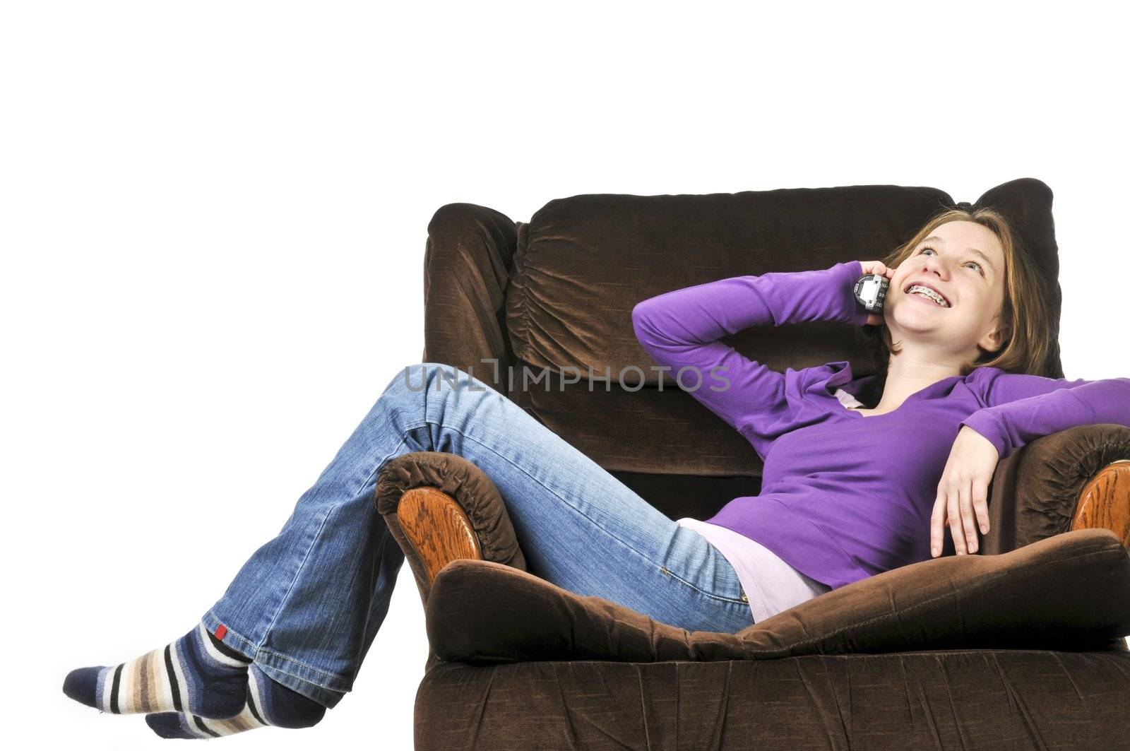 Teenage girl talking on a phone sitting in an armchair