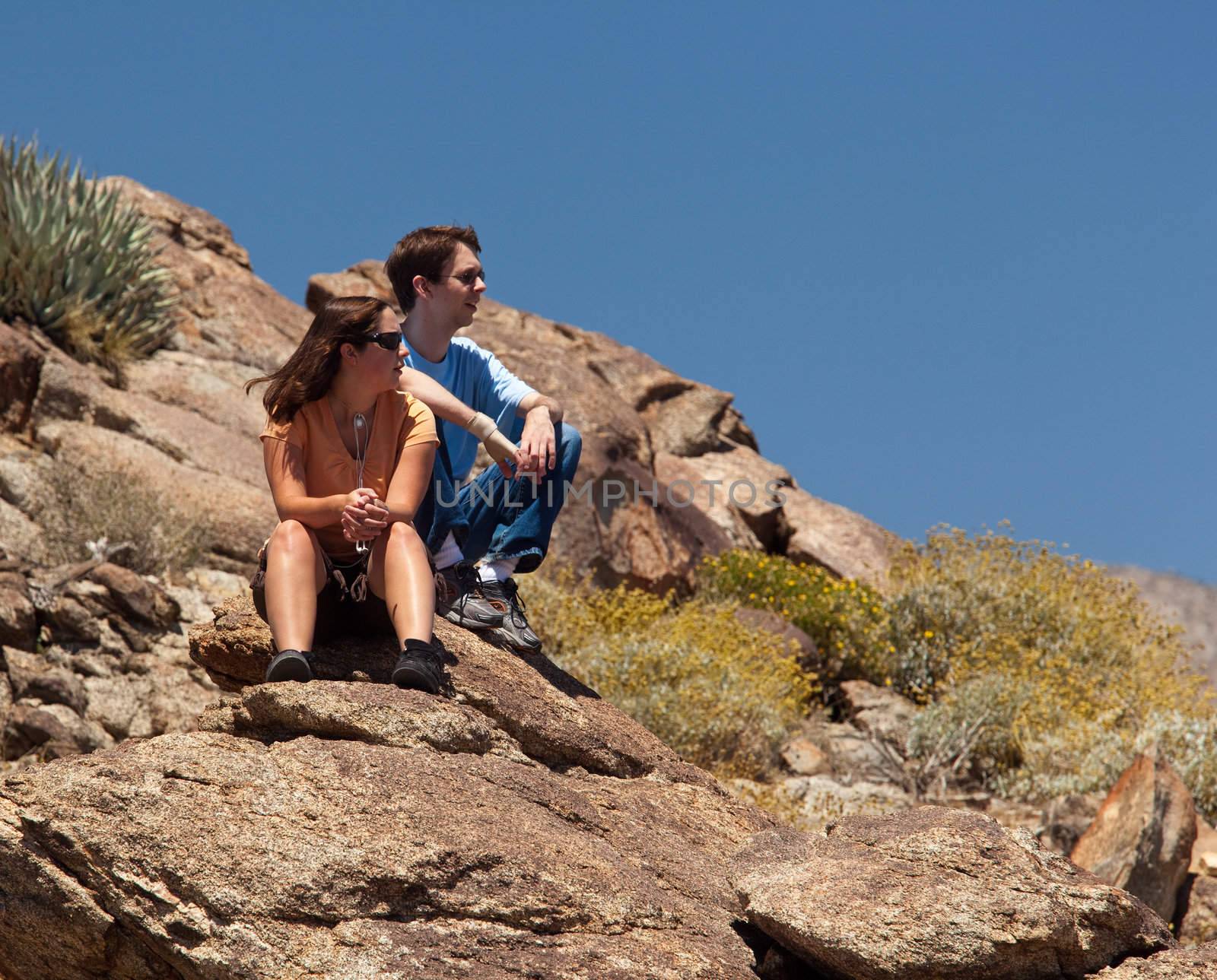 Hikers in desert look at distant object by steheap