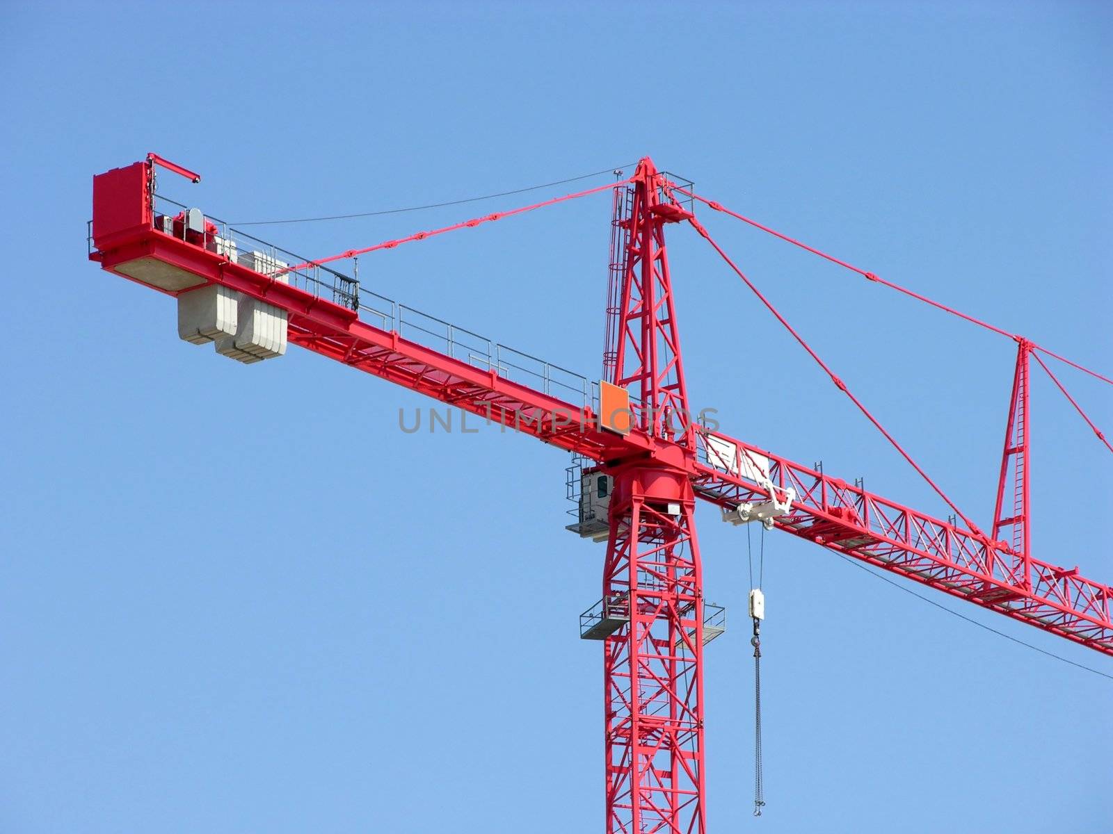 Tall red construction crane and blue sky