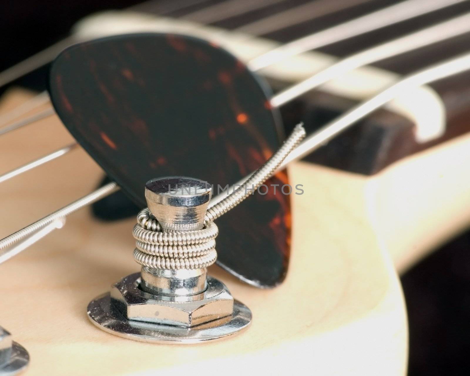 An electric guitar tuning peg with pick in the strings.