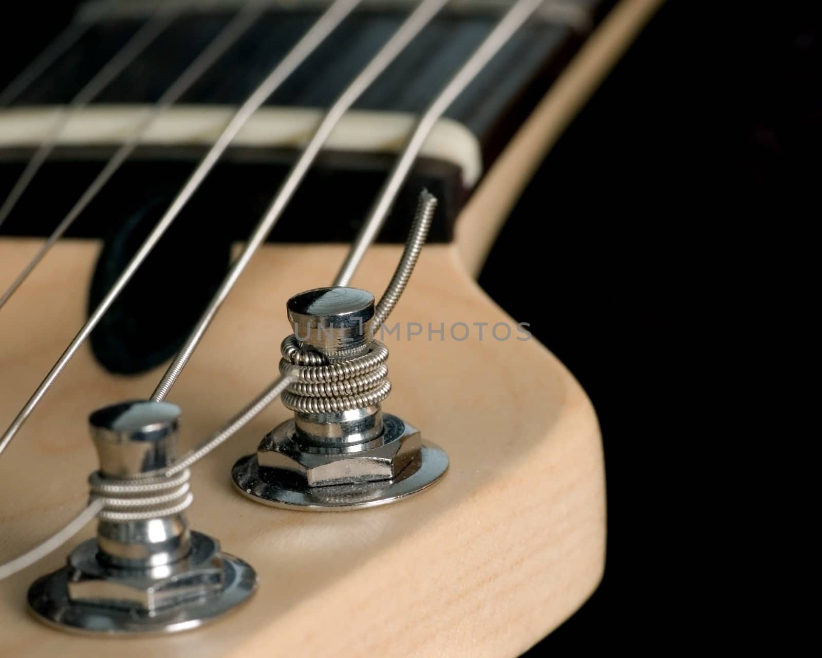 A macro closeup shot of an electric guitar head stock with string tuning pegs