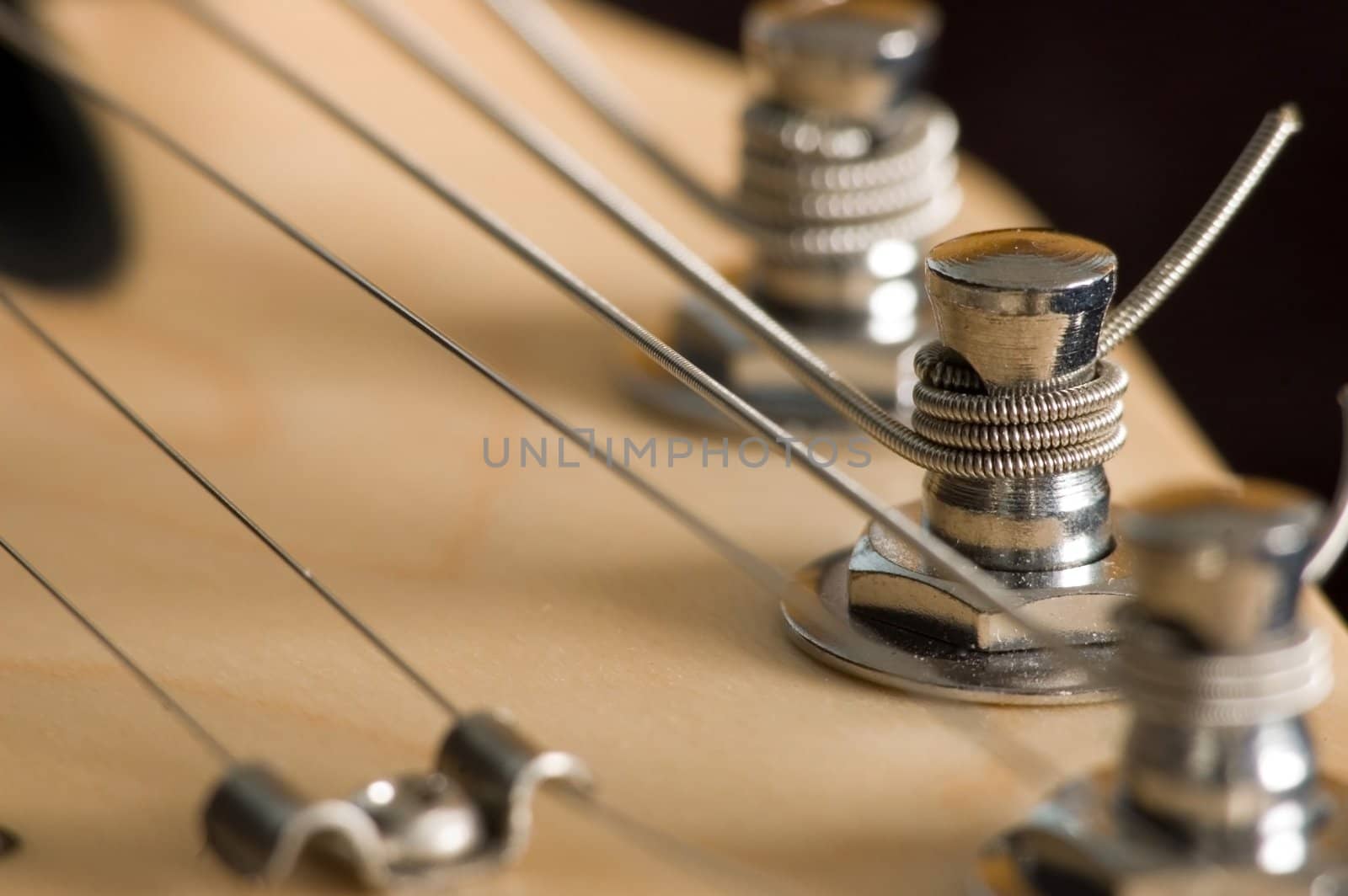 A macro closeup shot of an electric guitar head stock with string tuning pegs,