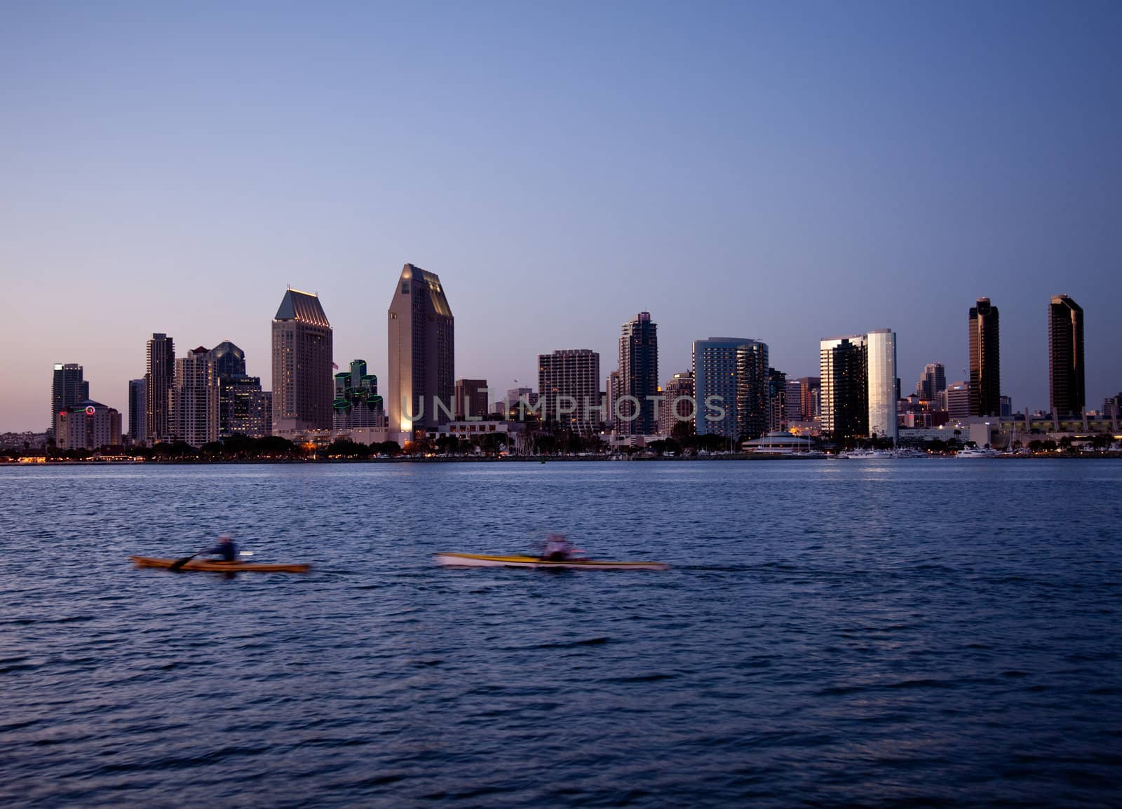 Sun setting lights up the buildings on San Diego seafront with kayaks and canoes