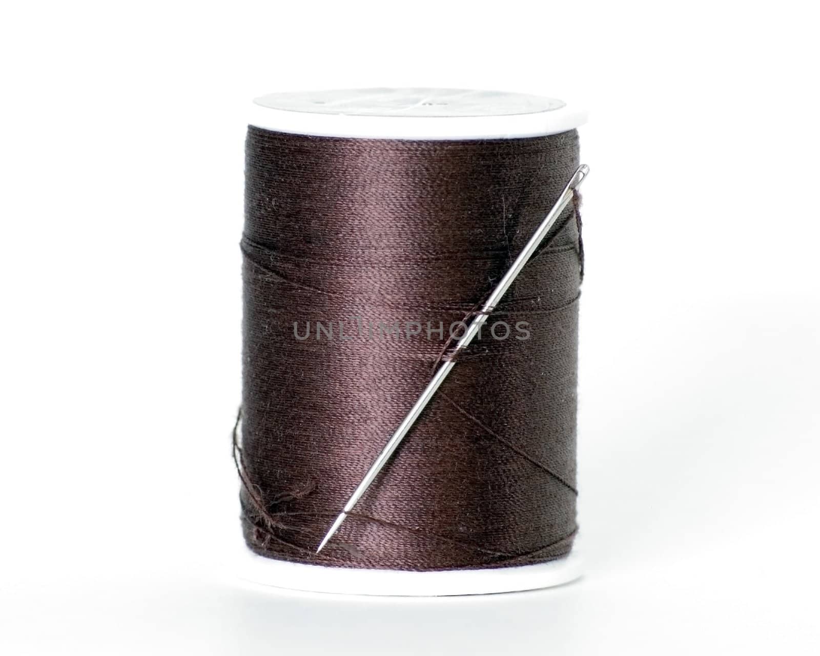 A spool of thread with a needle in it.