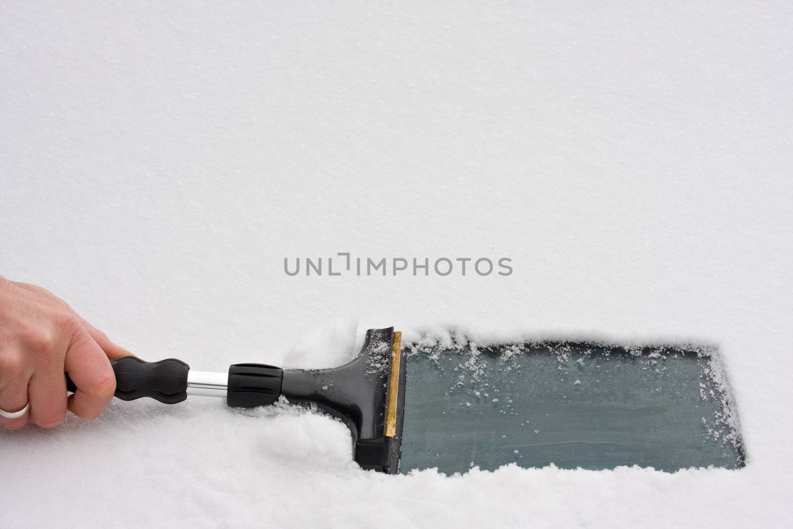 hand with an ice scraper cleaning a windshield by bernjuer