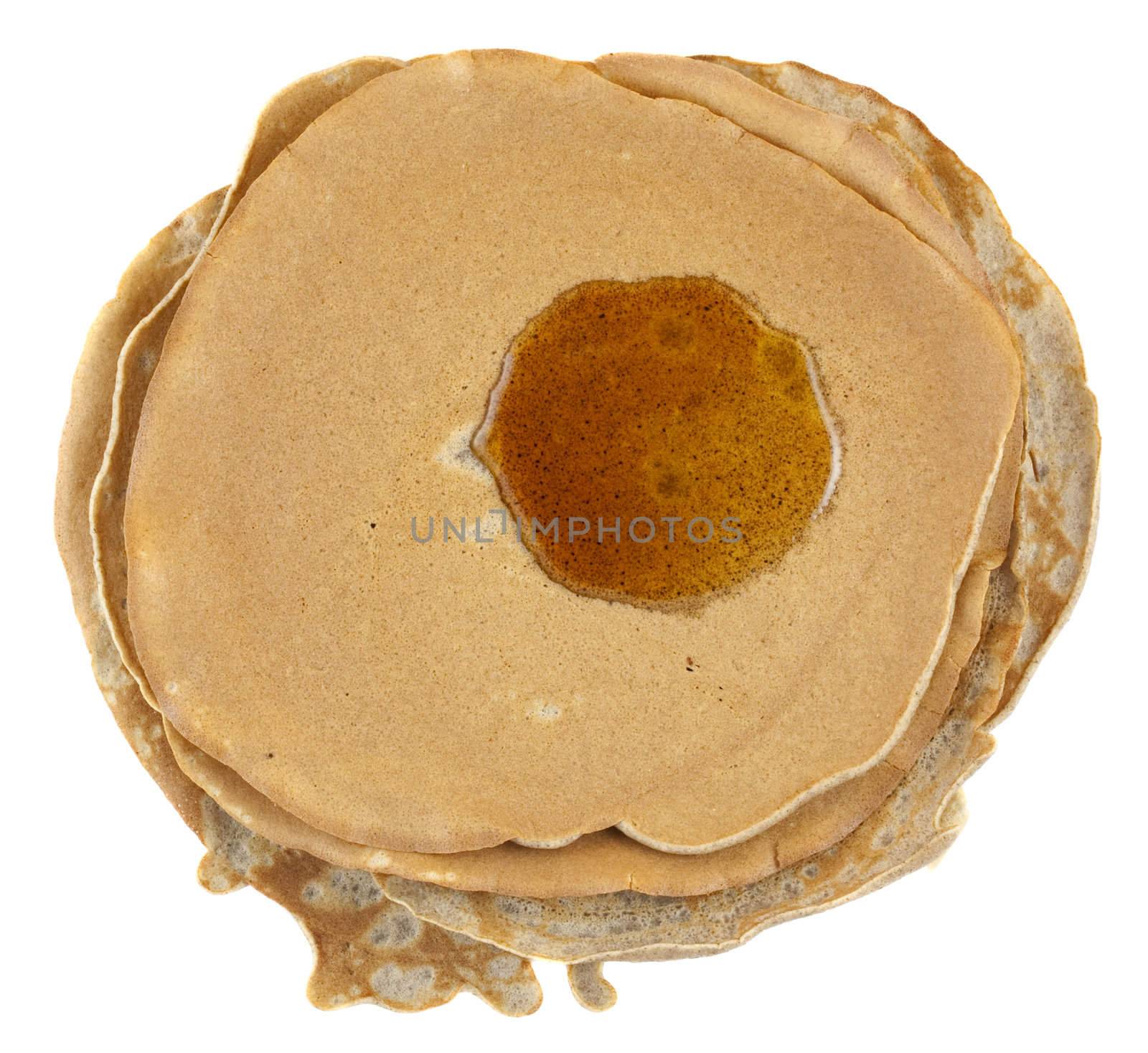 stack of homemade buckwheat flour crepes with irregular edges and maple syrup on top isolated on white