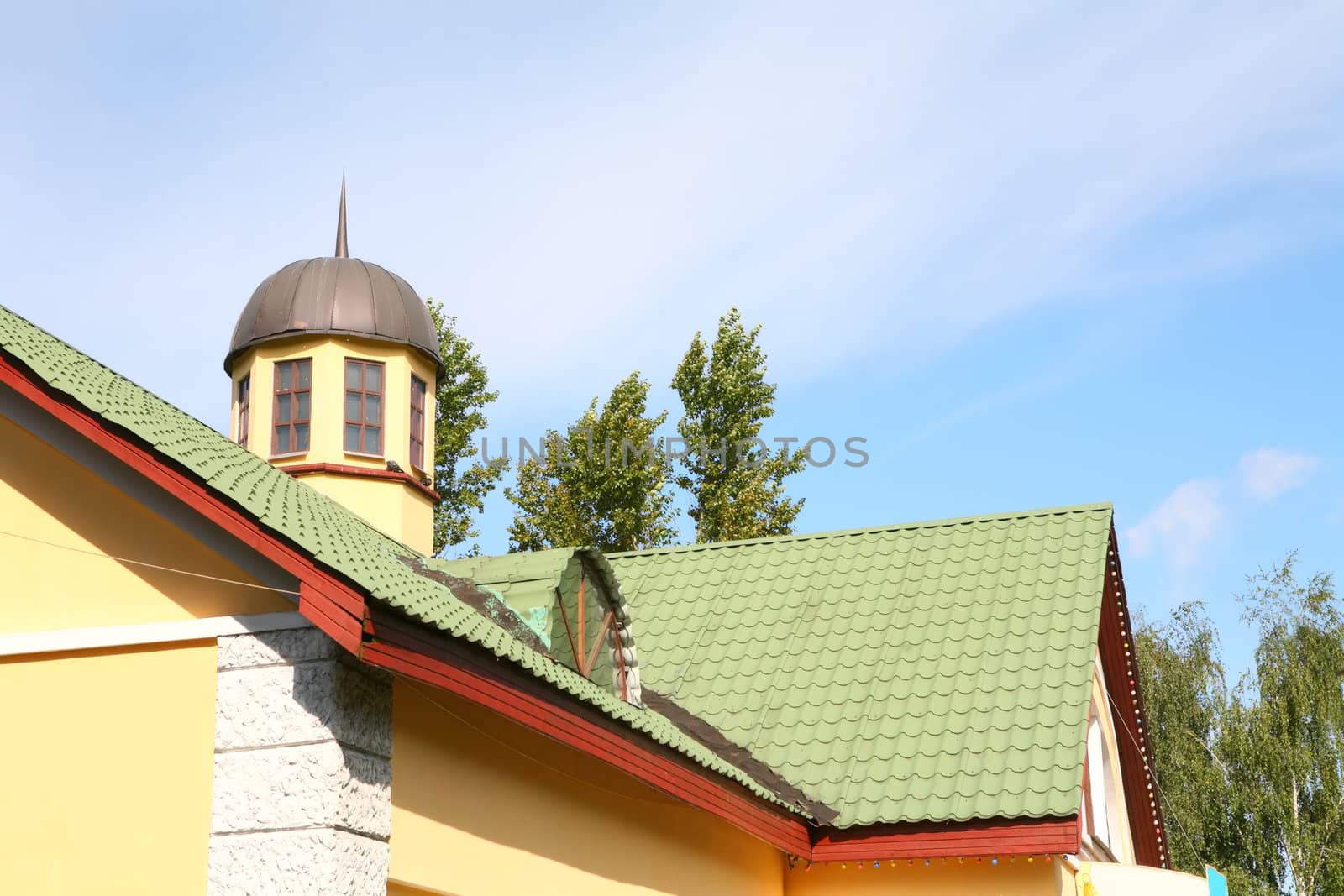 architecture, yellow house with green roof on background blue sky