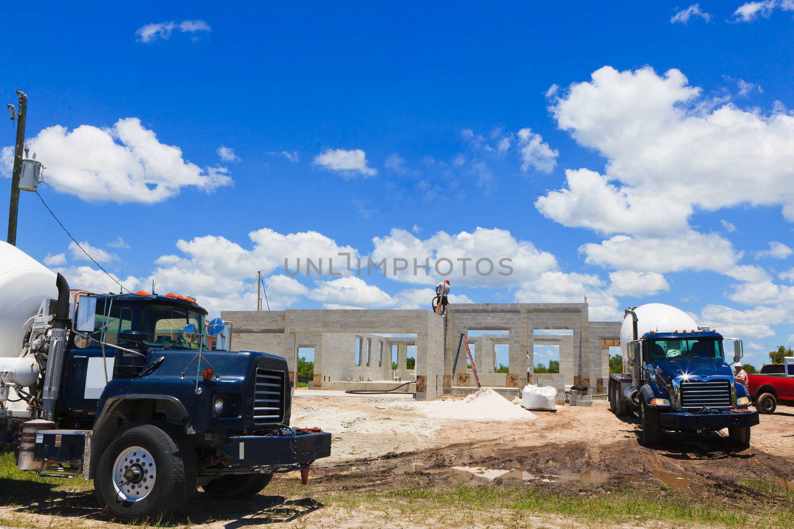 New cement block home with cement trucks and workers