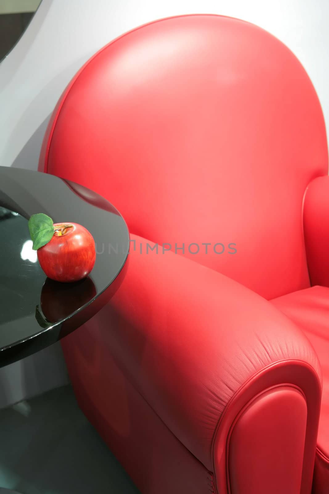 abstraction, fragment of the bright red leather easy chair with apple on edge of the table