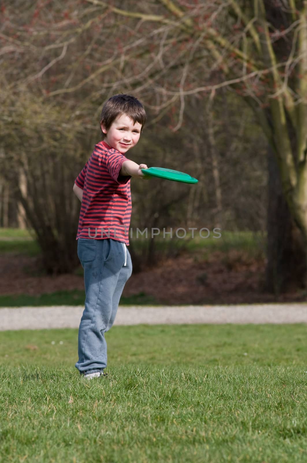 Boy in striped shirt throwing frisbe. by rongreer