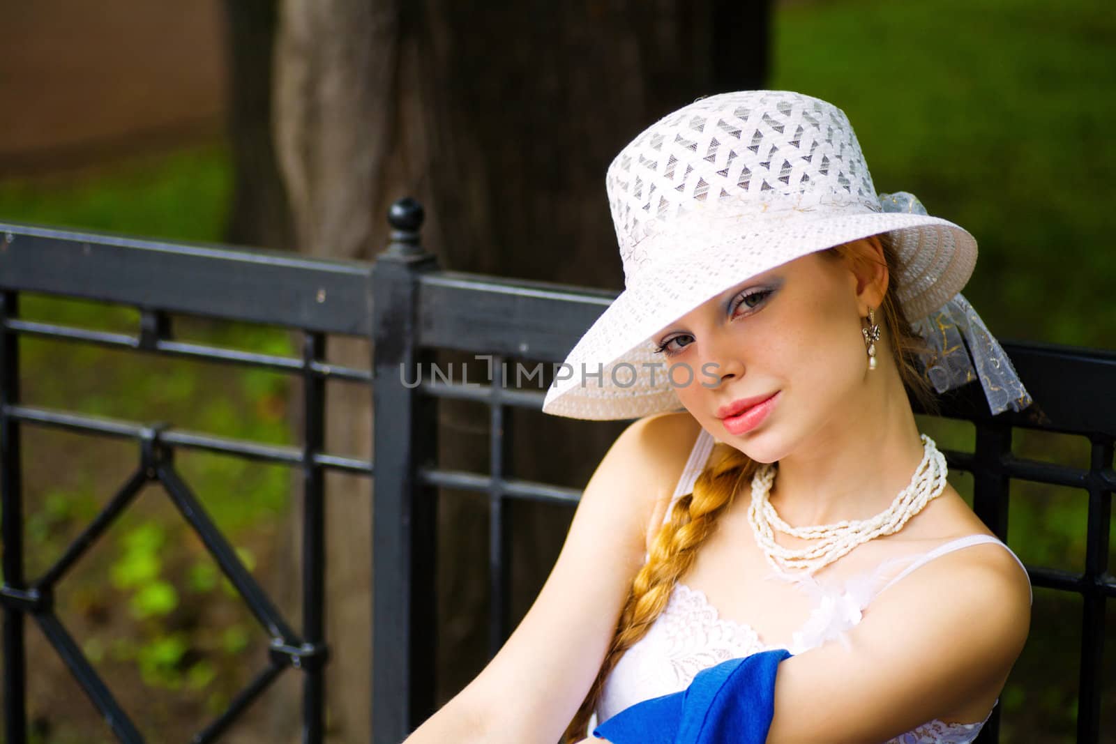 Young lady wearing white hat sitting on bench in park