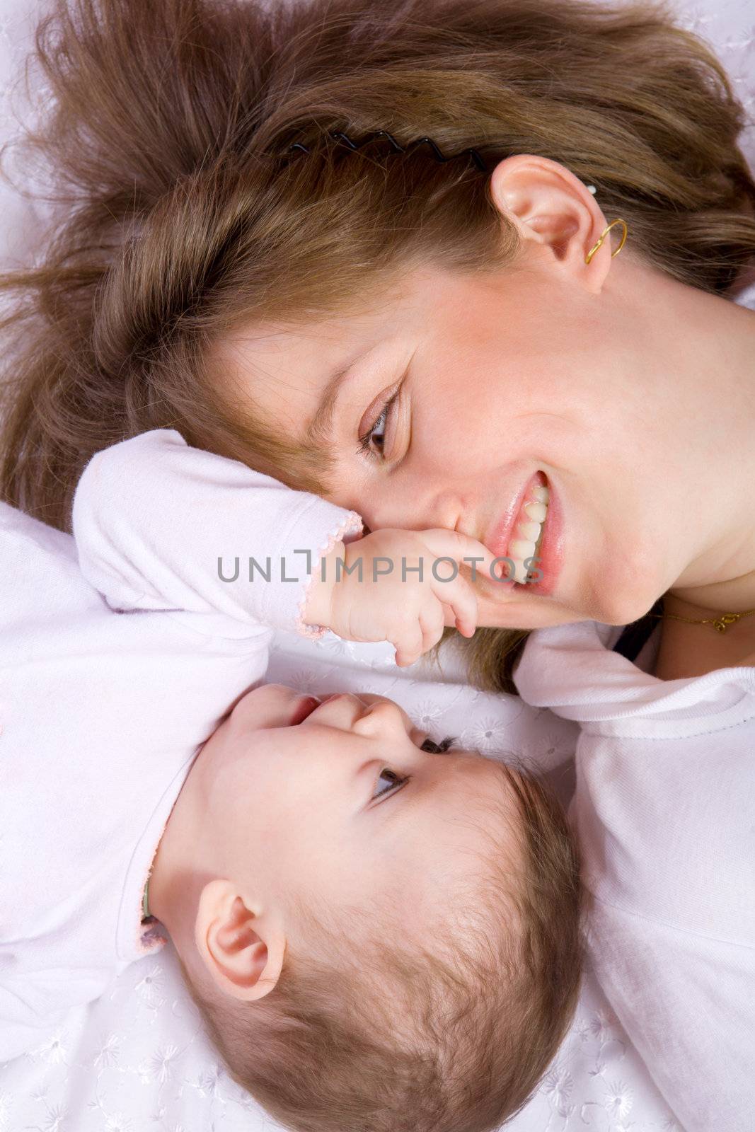 Happy Mother playing with seven month baby lying on floor