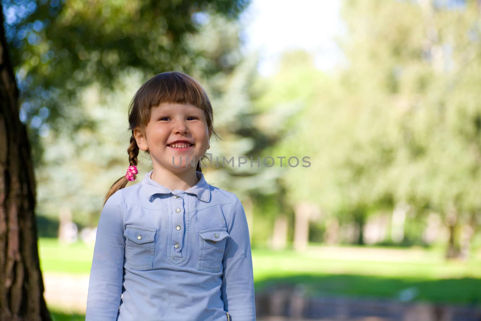 Laughing little girl standing near the tree