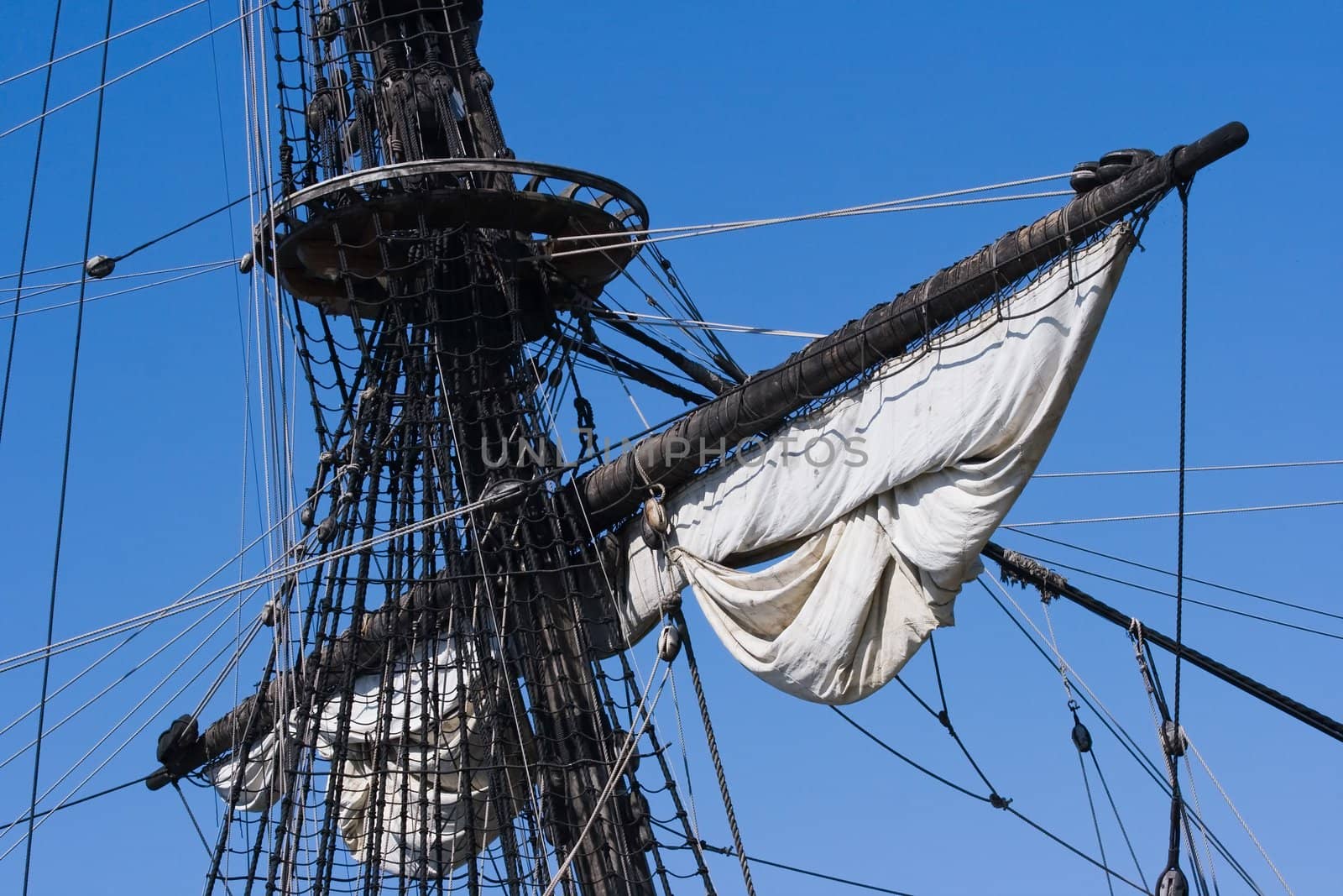 Mast, ropes and sails from old sailingship on a blue sky background