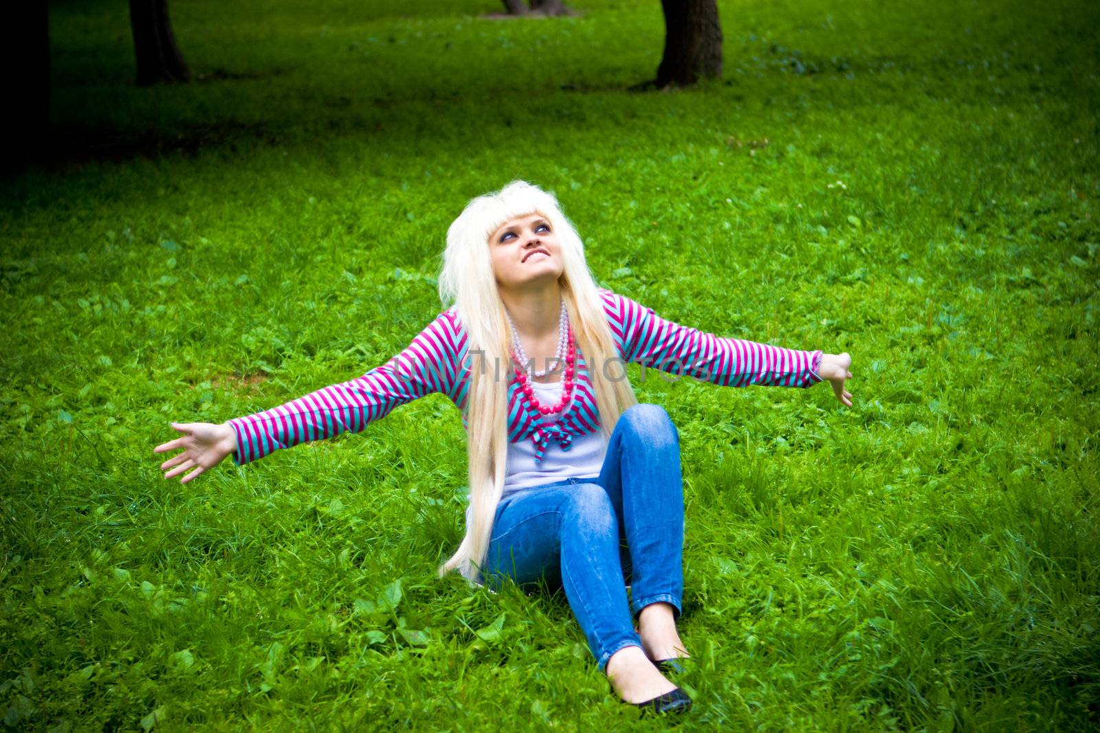 Happy young blond woman looking at you in park