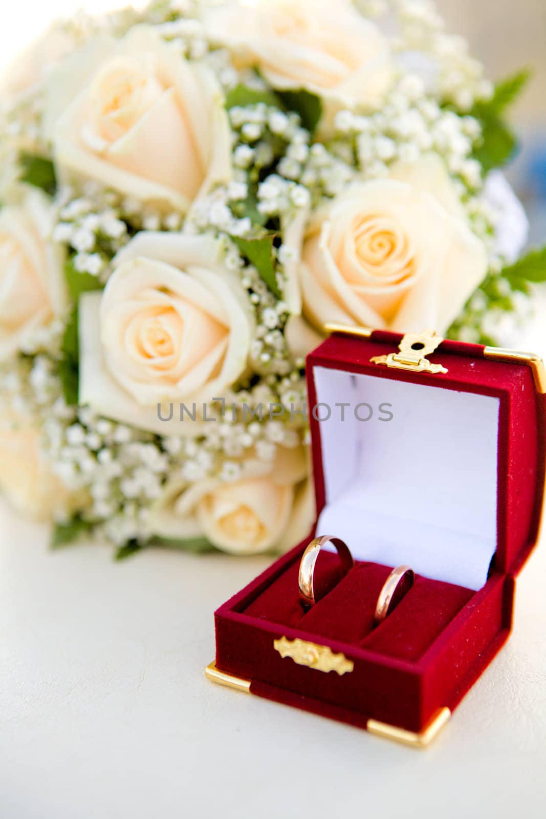 wedding rings in red box near bouquet on table