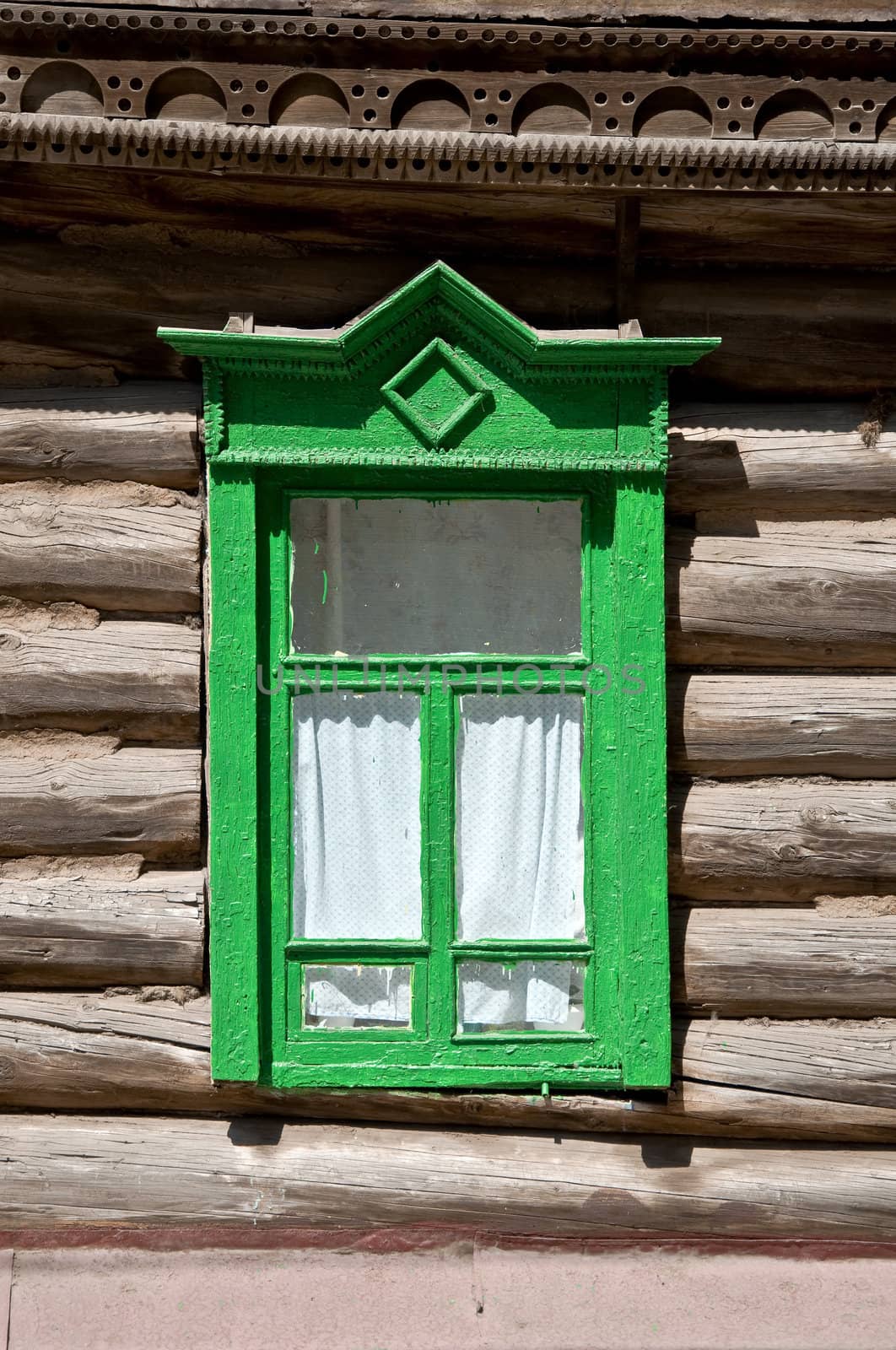 Old window in the log house. Close-up, a fragment of the facade. Russian province.