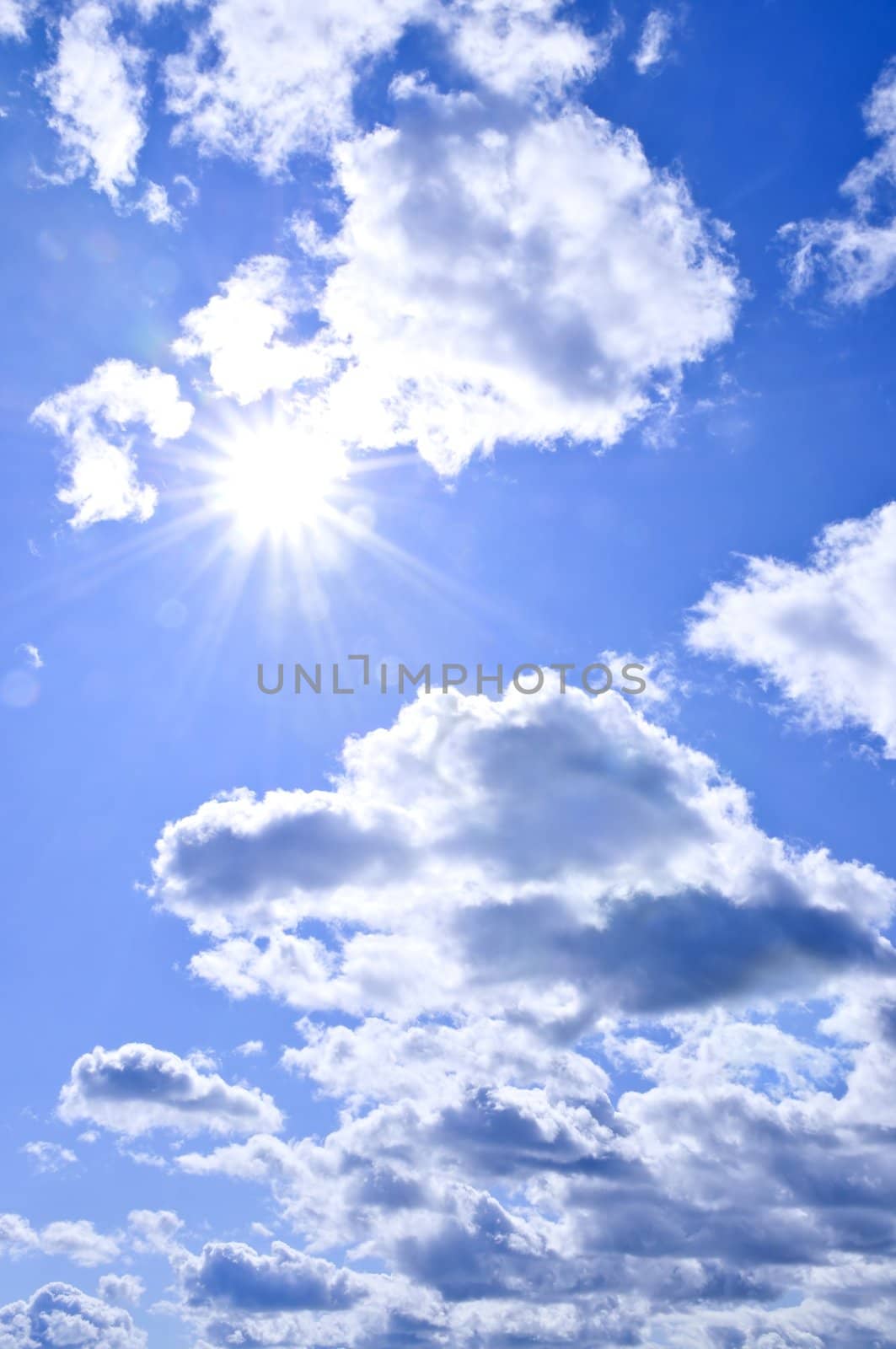 Background of blue sky with shining sun and clouds