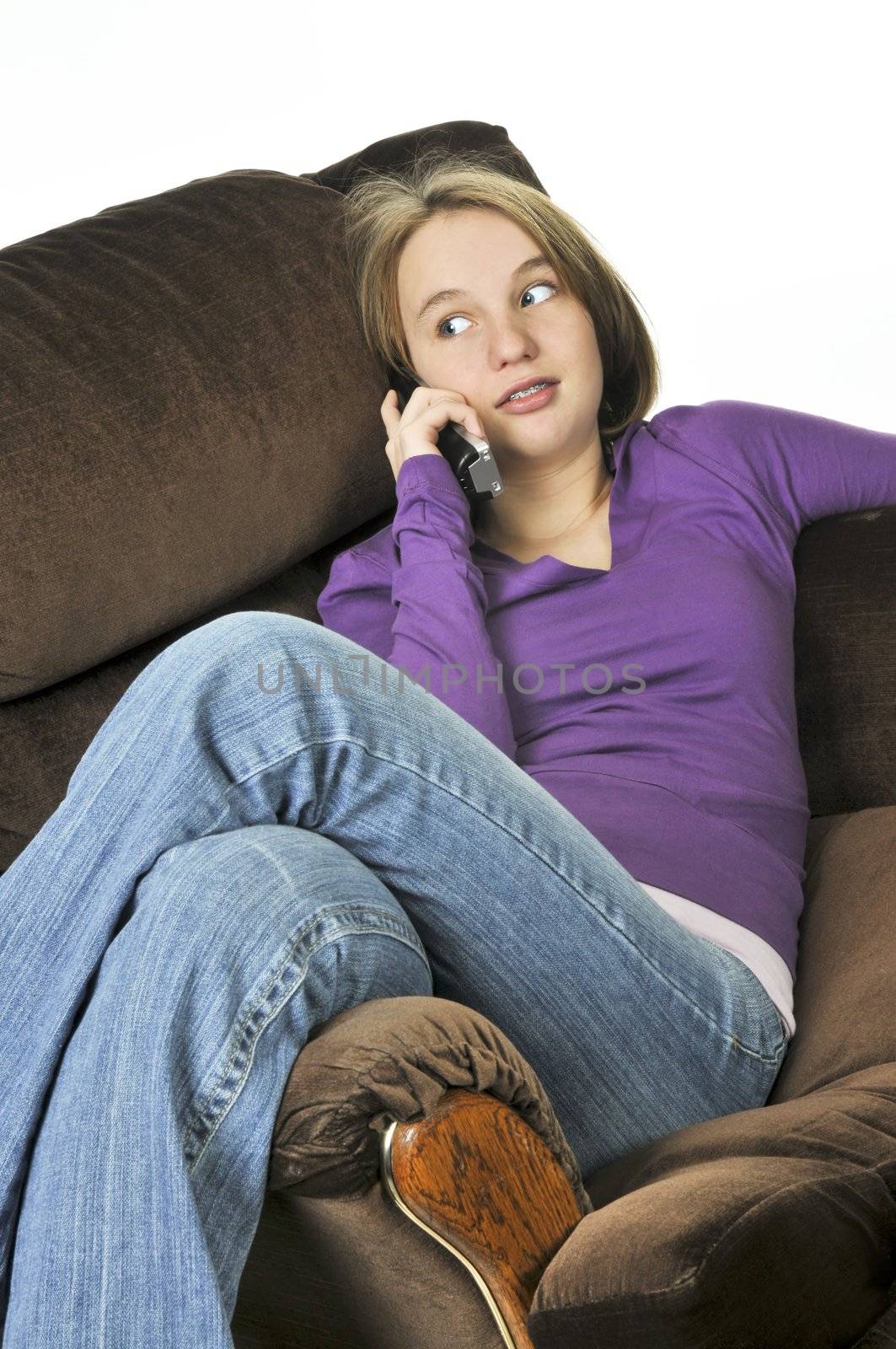 Teenage girl talking on a phone sitting in an armchair