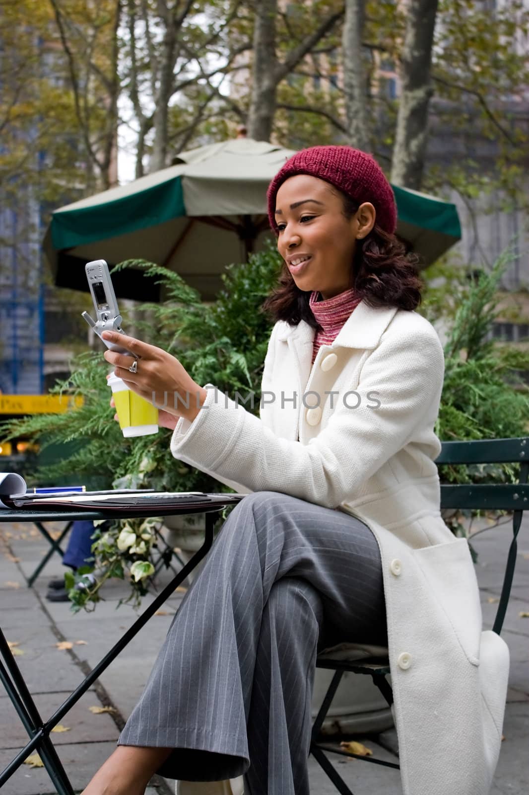 An attractive business woman checking her cell phone in the city.  She could be text messaging or even browsing the web via wi-fi or a 3g connection.