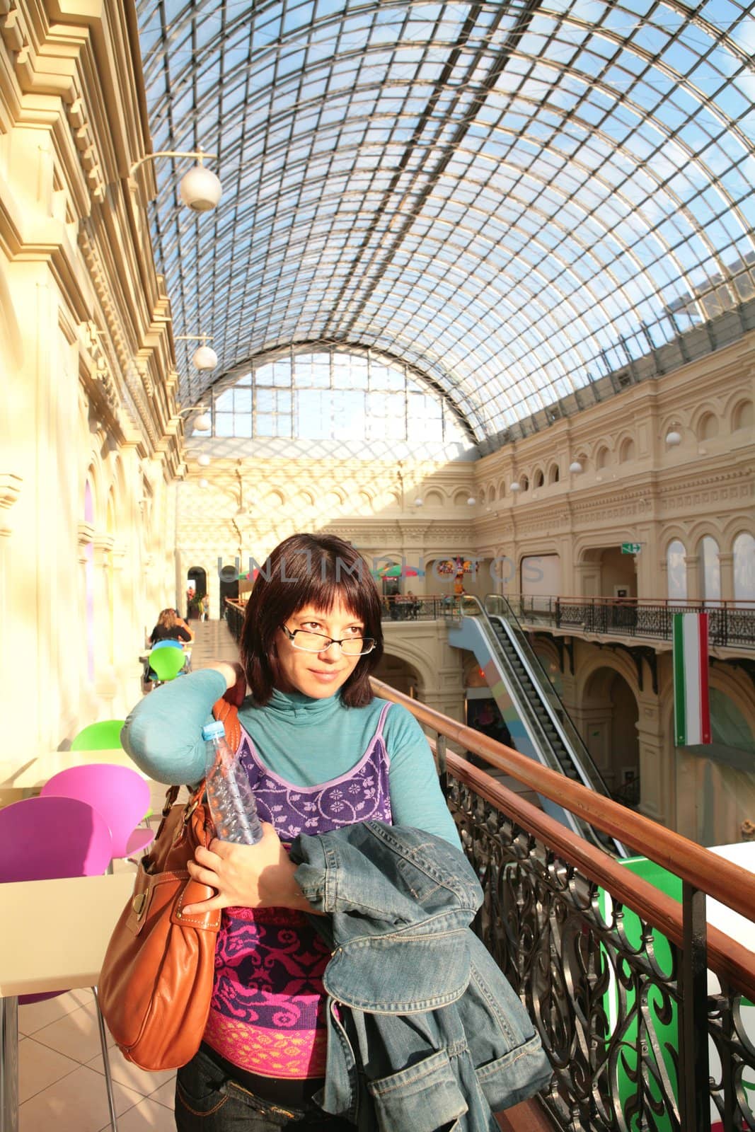 smiling expectant mother under glass ceiling of the old-time shopping center, GUM, Moscow