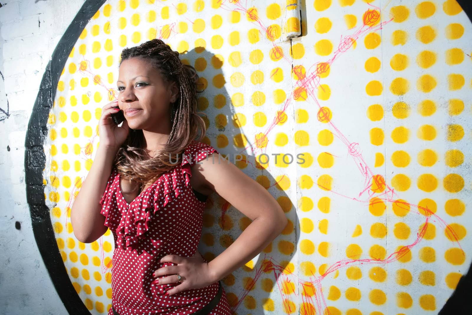 girl in polka dress talks on mobile phone on background of the graffiti