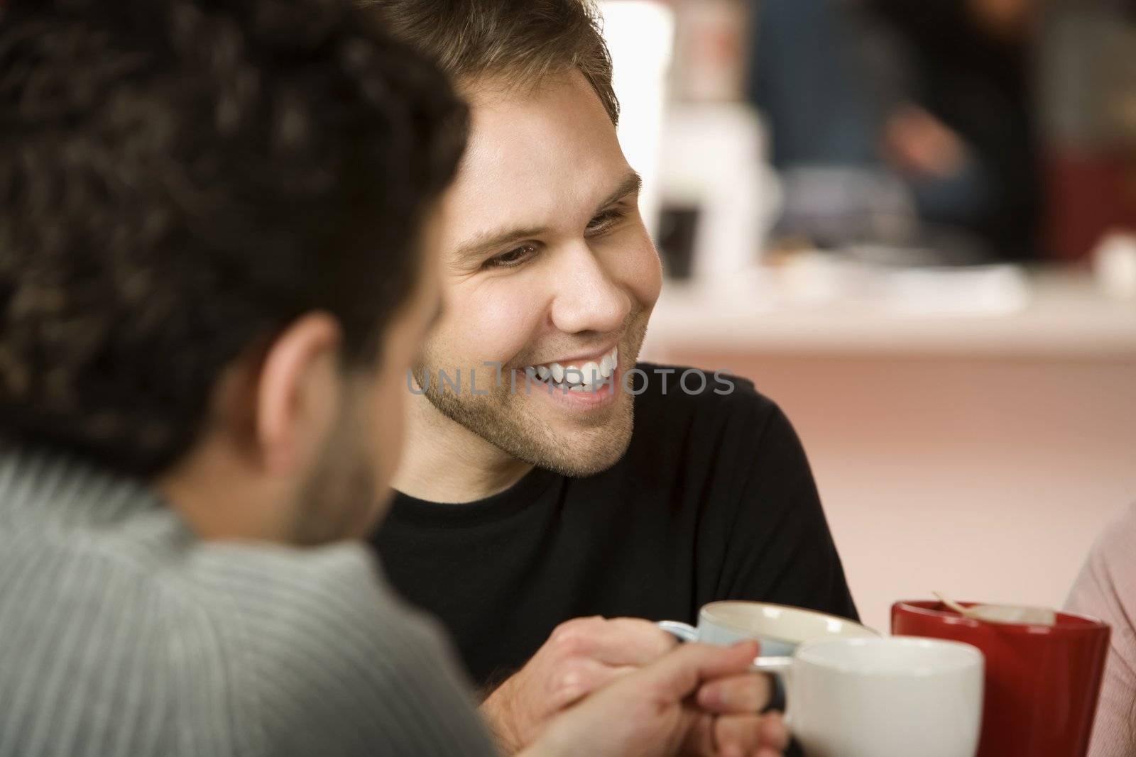 Young man toasting friends with coffee cups