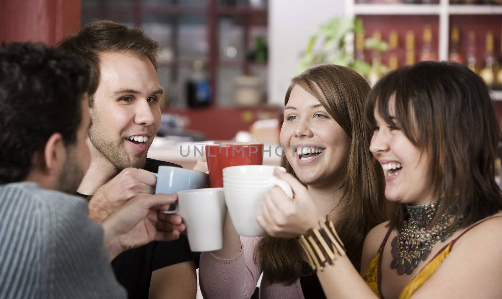 Young toasting friends with coffee cups in a cafe