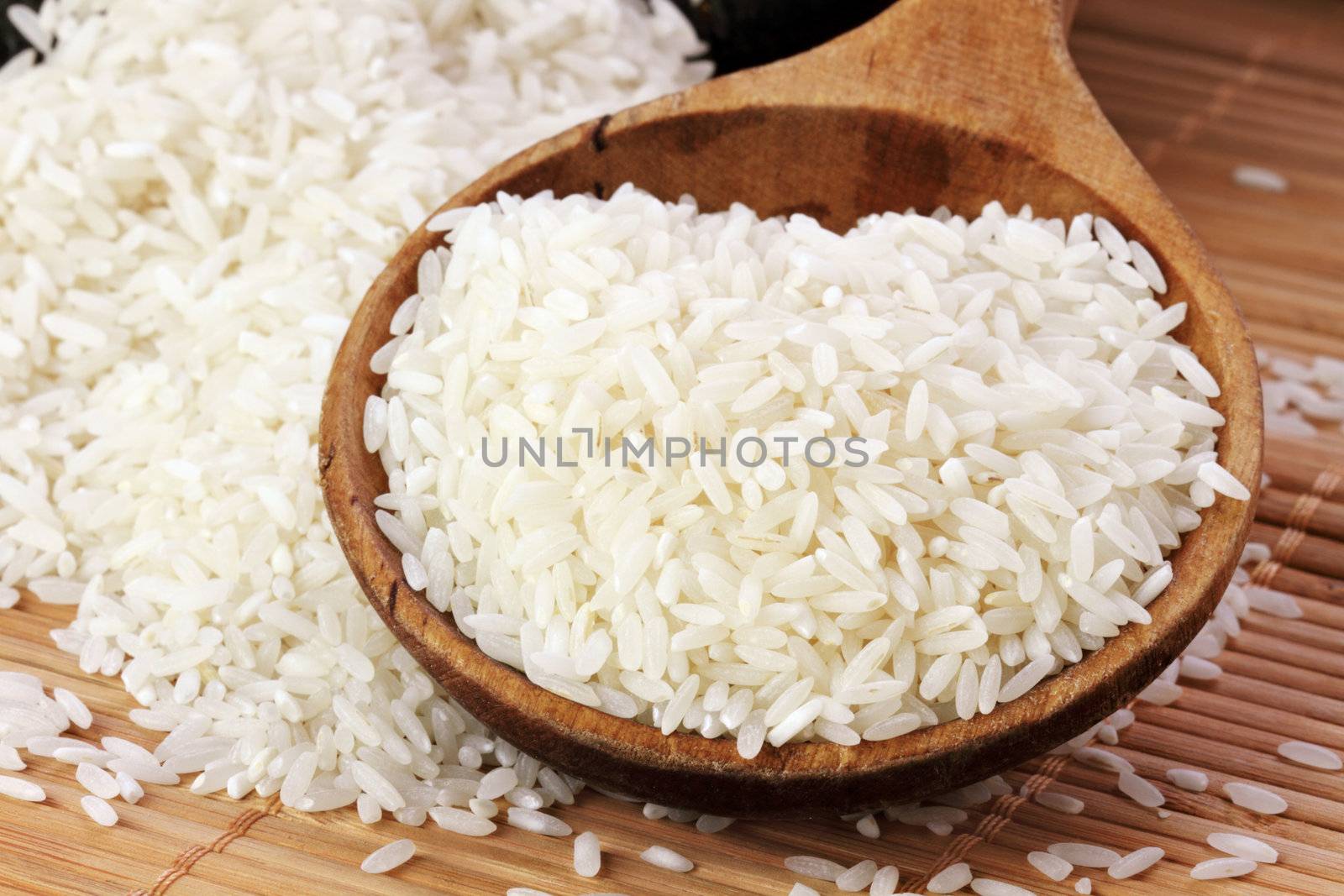 Uncooked white rice in a wooden spoon. Shallow DOF.