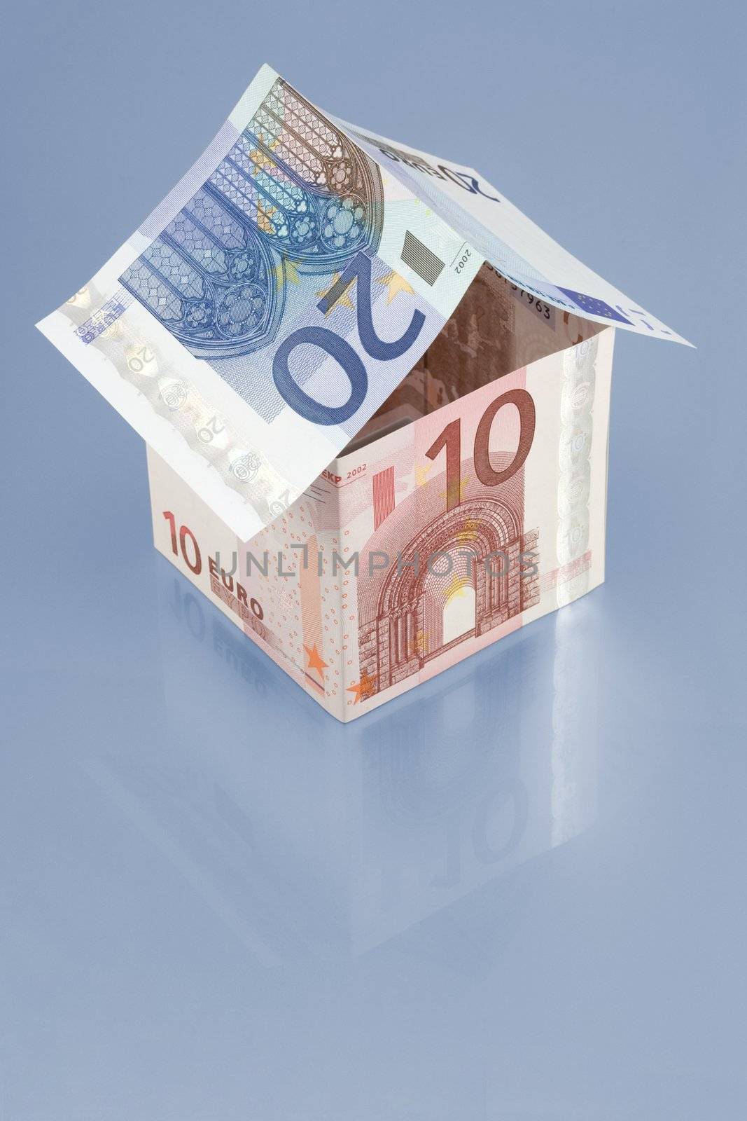 House made of euro bills over reflective surface