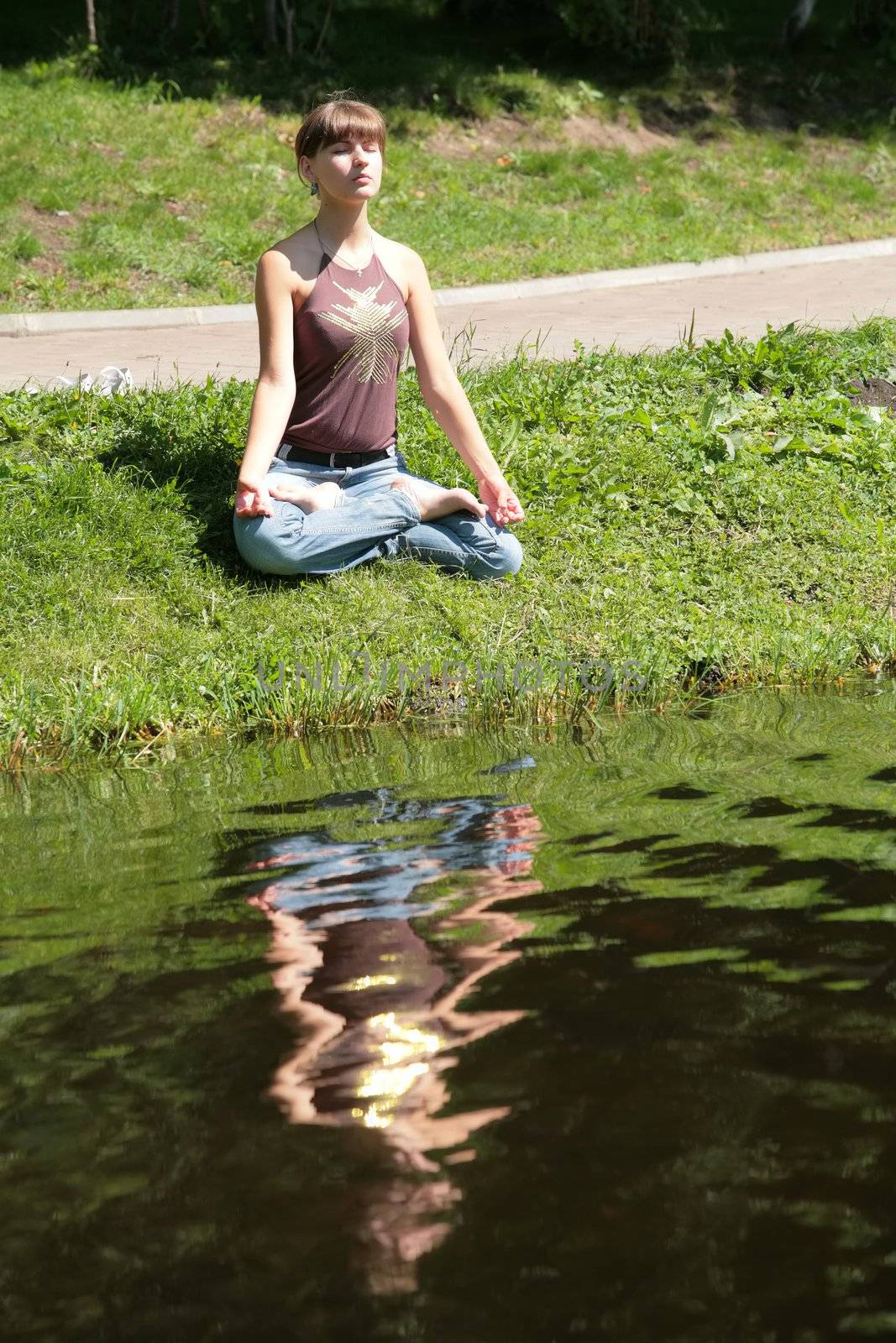 beautiful girl meditating near by water with reflections