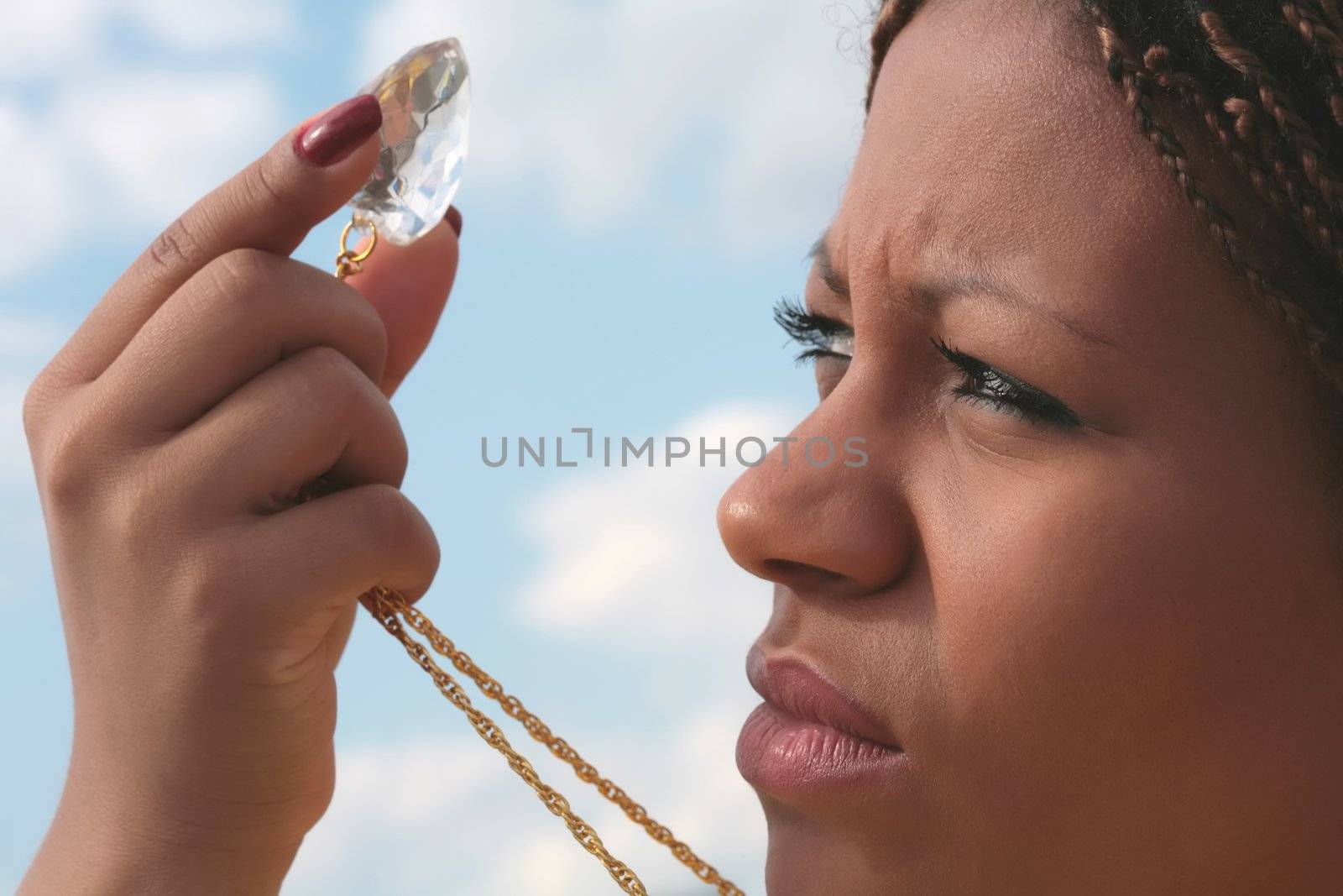 african girl keeps finger large diamond and looks through it on light