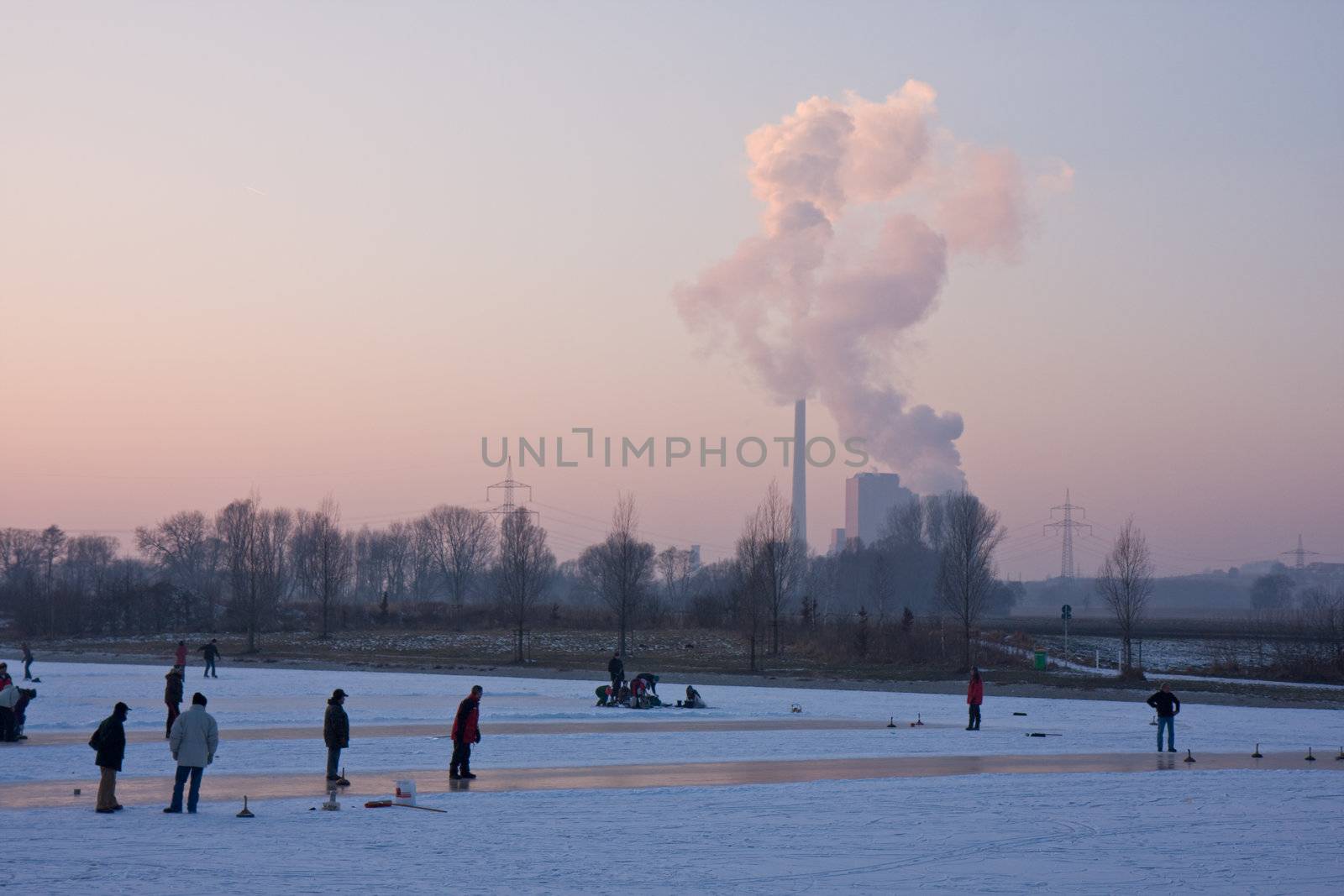 two curling stones on a frozen lake at sunset by bernjuer