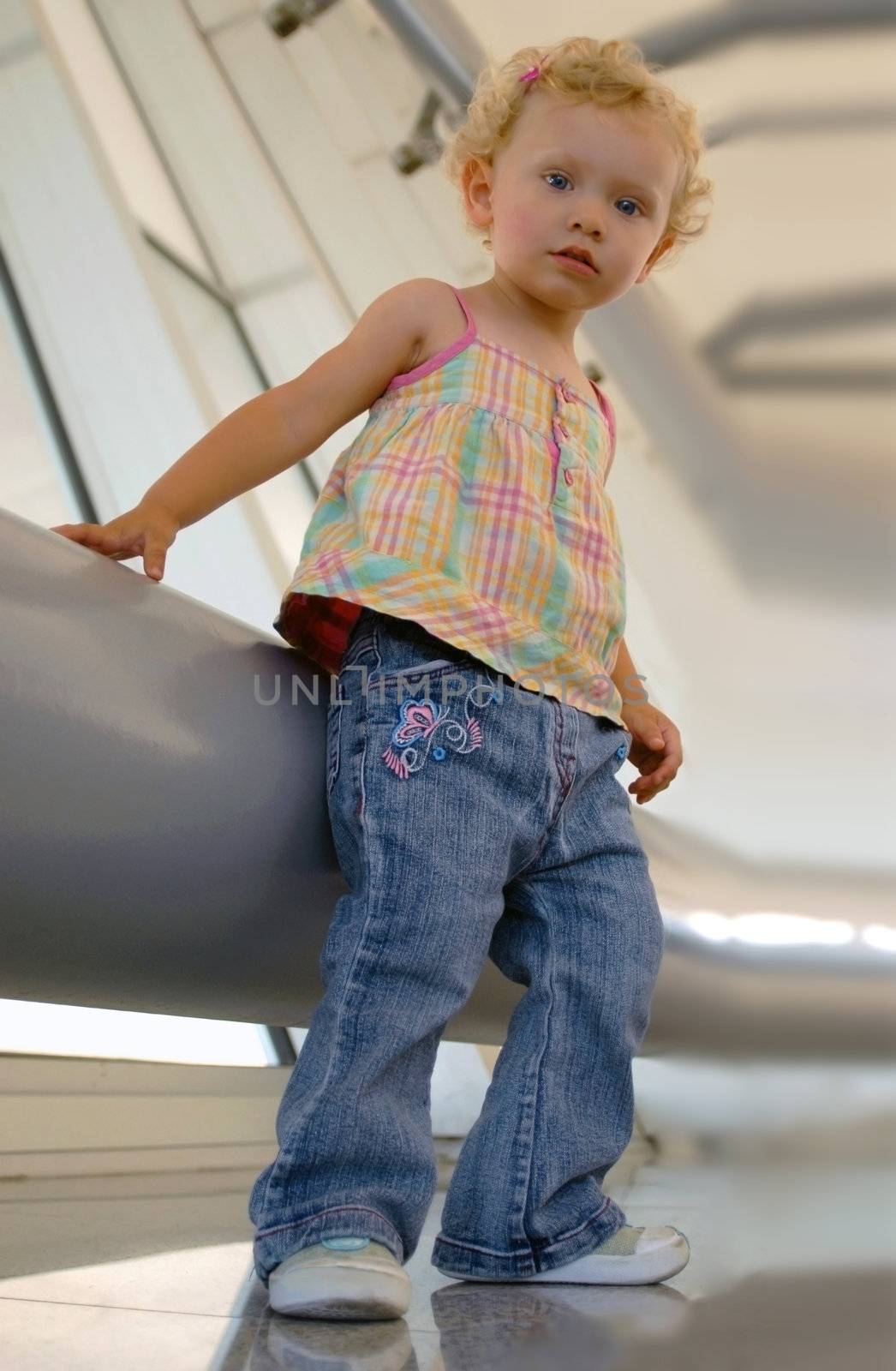 One blondie girl standing next a large metal tube at industrial set. Looking at the camera from bottom view.