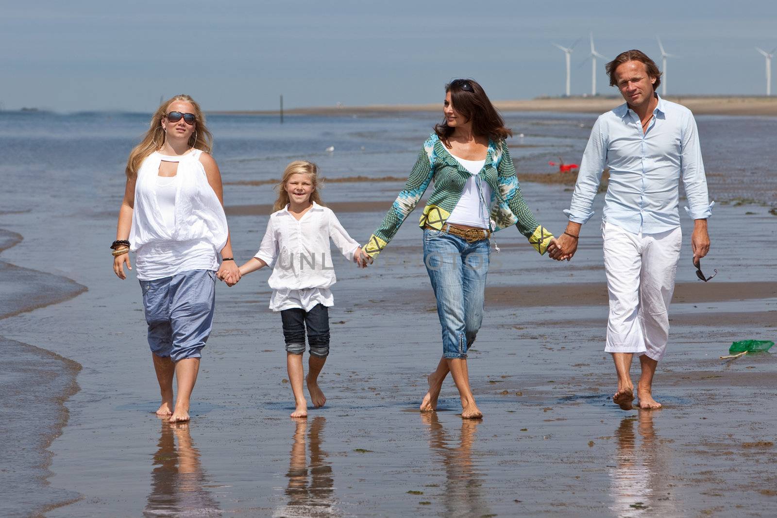 Young family walking along the beach together holding hands