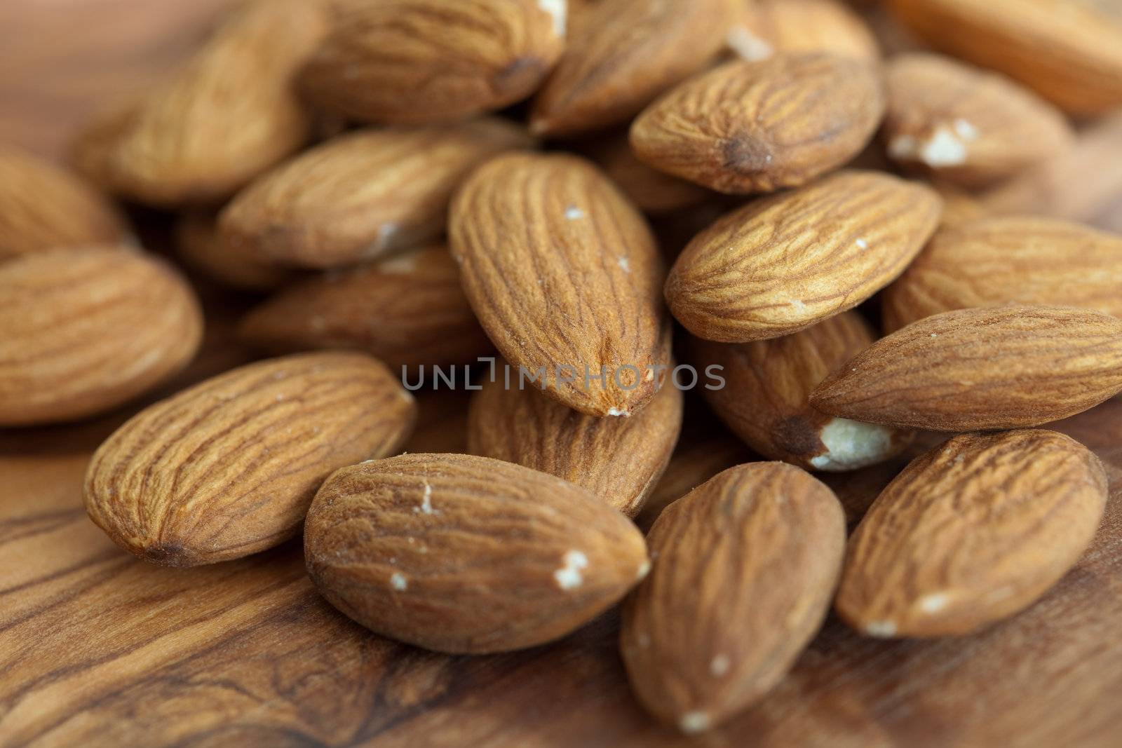 Delicious almonds with peel still on in a pile on wooden surface
