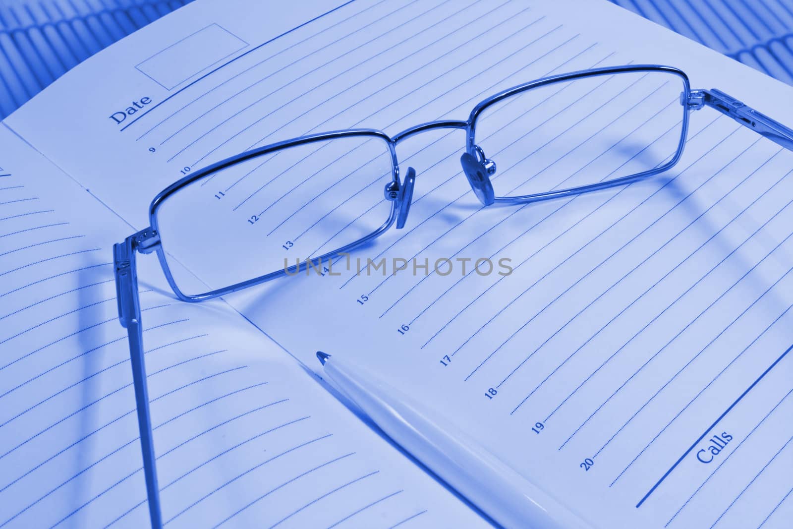 Glasses, pen and notebook, photographed close up.