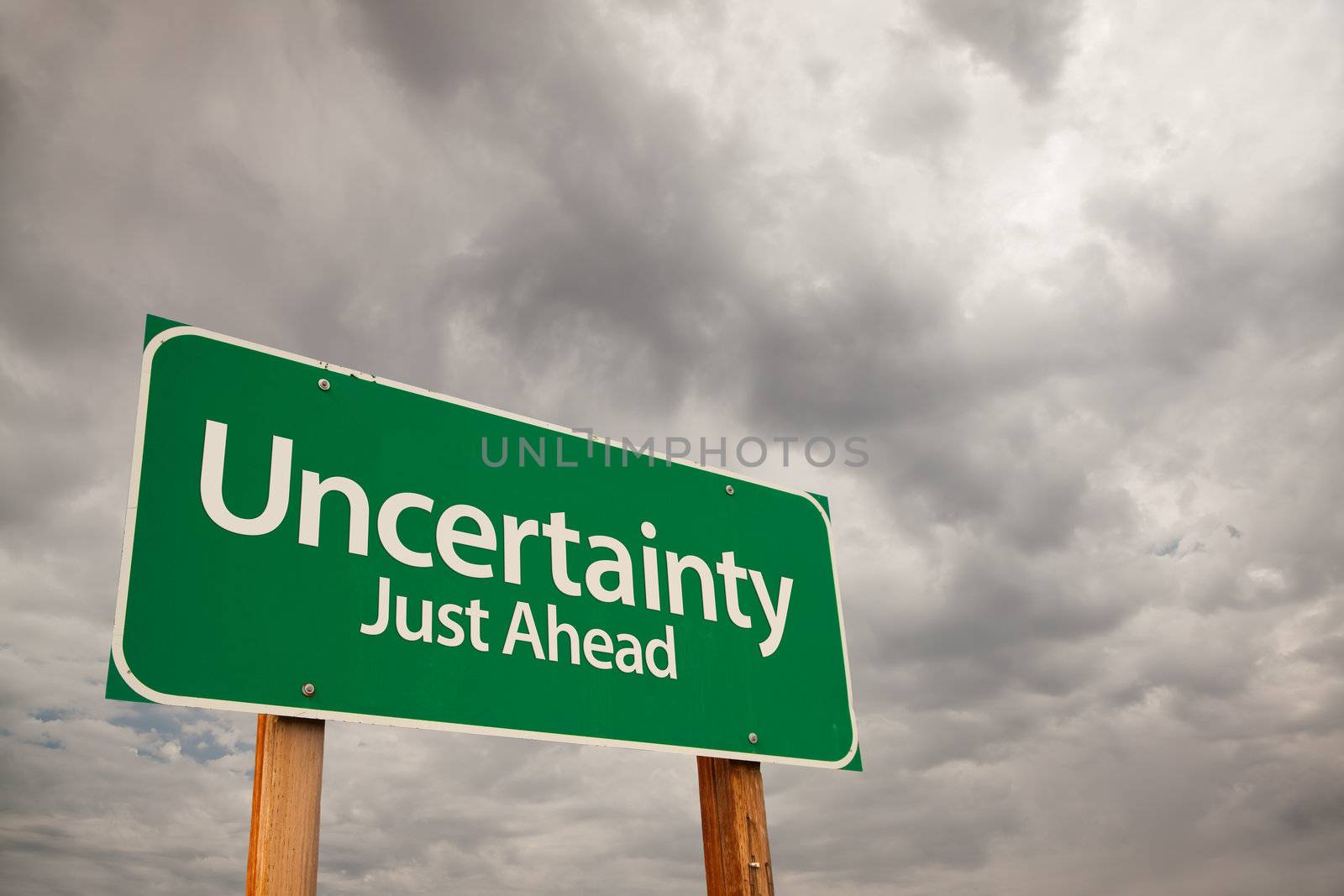 Uncertainty Just Ahead Green Road Sign with Dramatic Storm Clouds and Sky.
