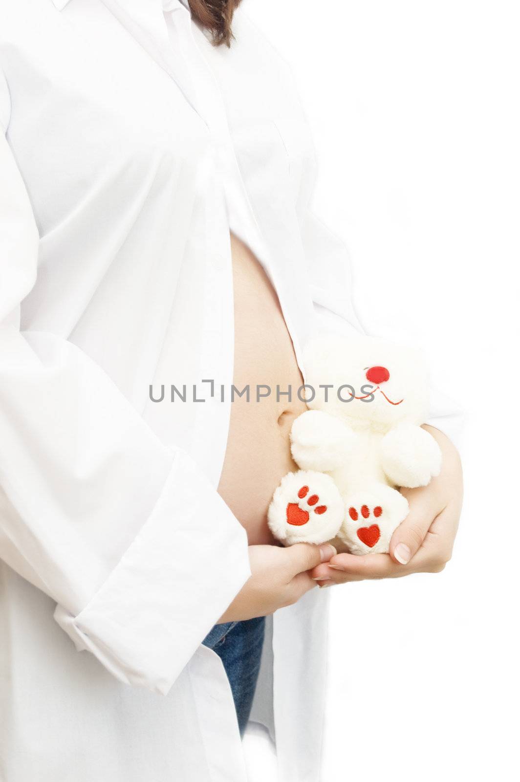 Woman hands holding pregnant belly with toy over white